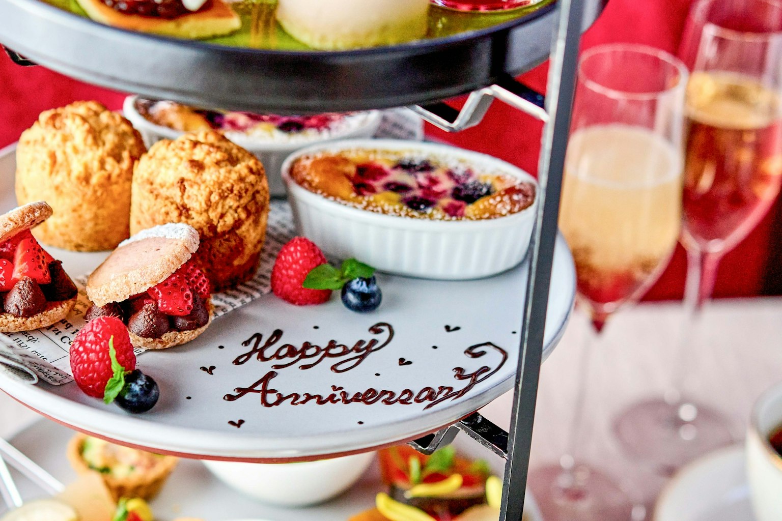 Una bandeja de postres de aniversario bellamente arreglada con pasteles y champán