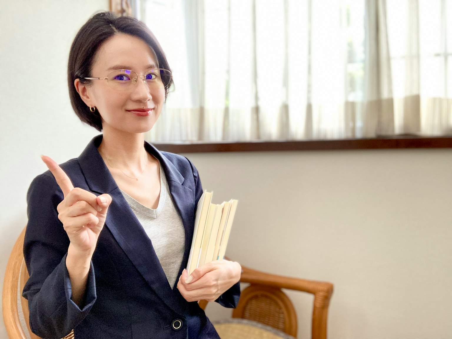 Người phụ nữ trong bộ vest cầm sách và giơ ngón tay
