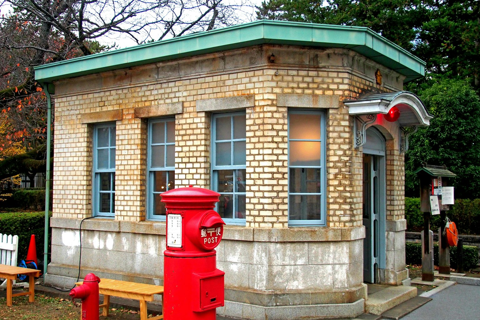 Petit bâtiment de bureau de poste en briques avec une boîte aux lettres rouge distincte