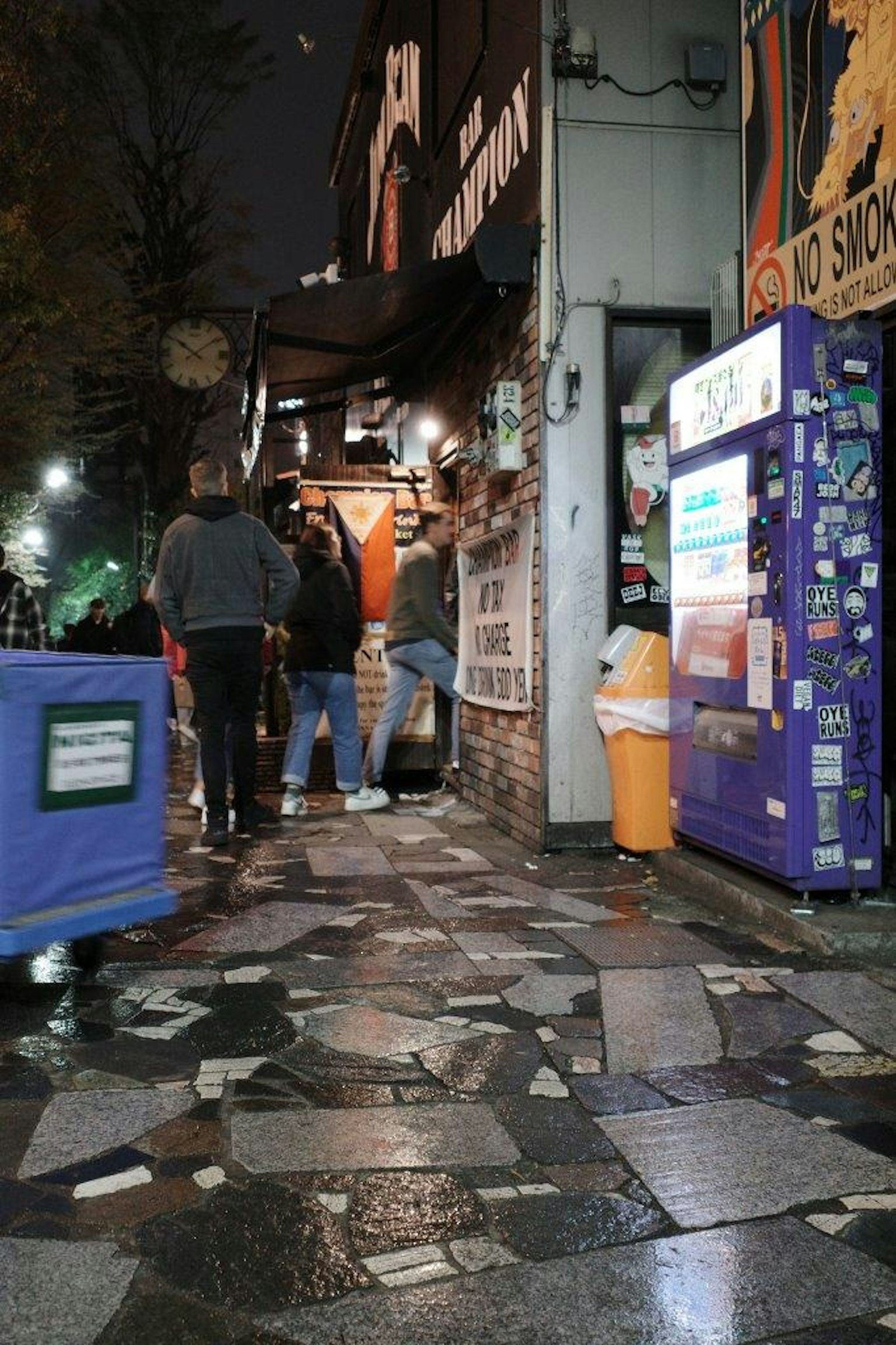 夜晚的街角，商店和人们在铺砖的人行道上