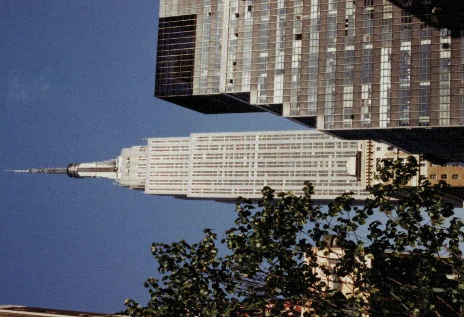 Empire State Building avec des bâtiments environnants et un ciel bleu clair