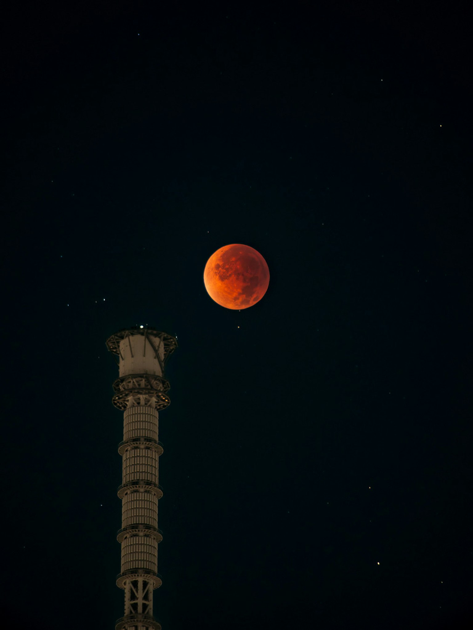 Lune rouge dans le ciel nocturne au-dessus d'une tour