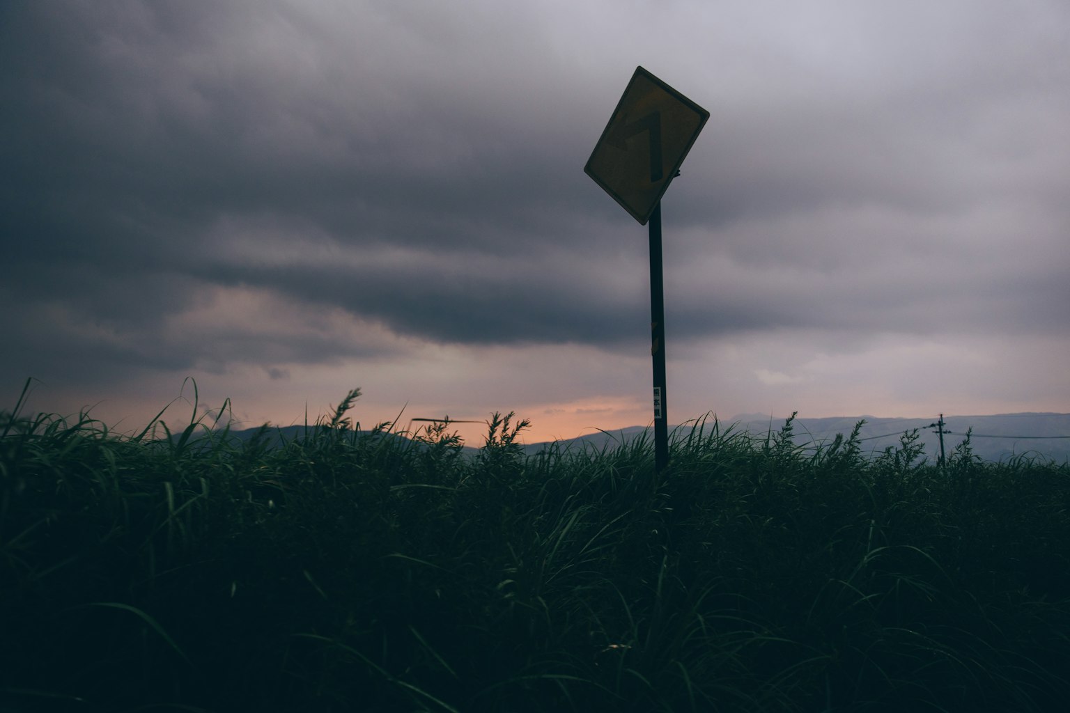 Una señal borrosa se erige en un campo bajo un cielo crepuscular sombrío