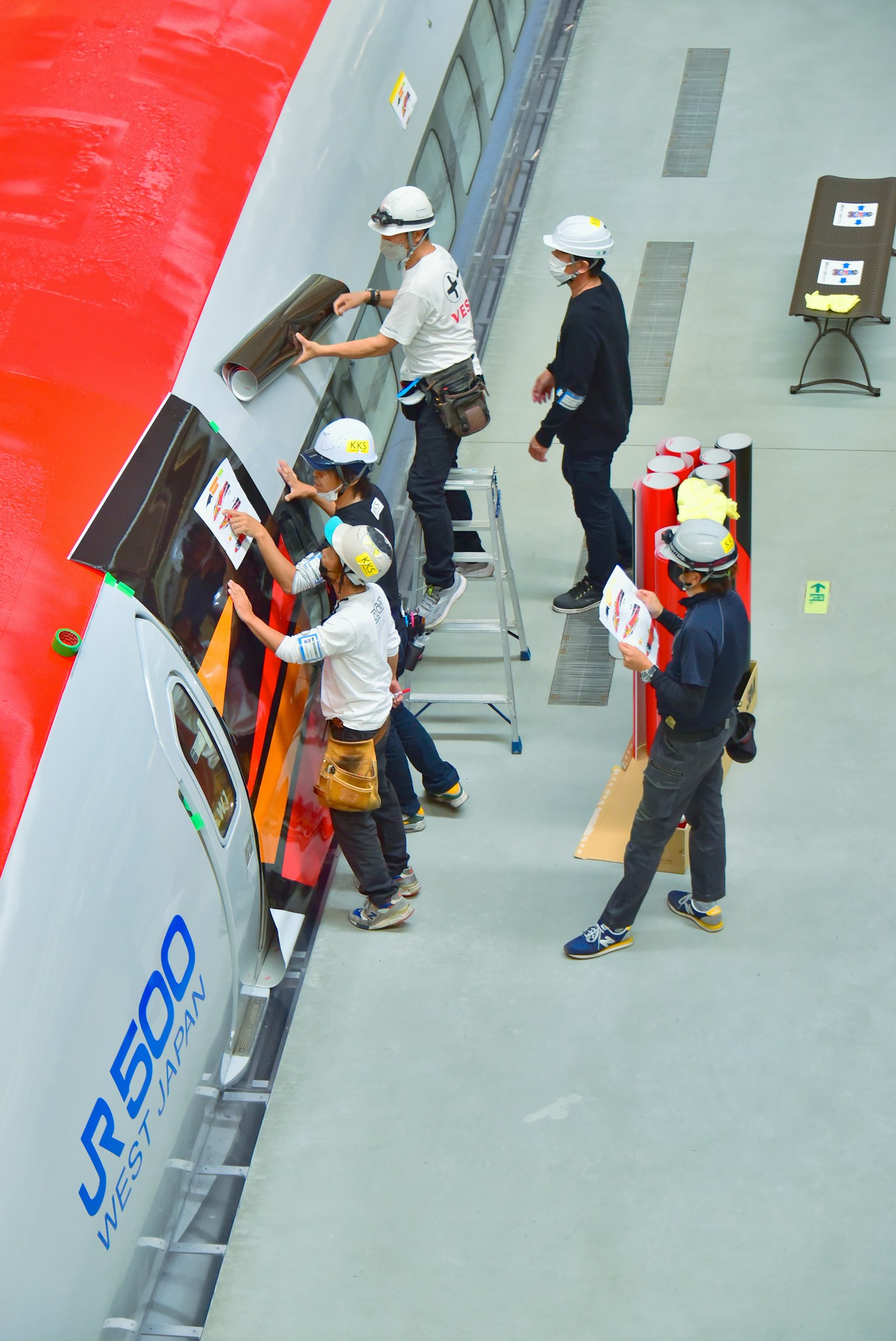 Des travailleurs appliquent des autocollants sur l'extérieur du train Shinkansen JR500