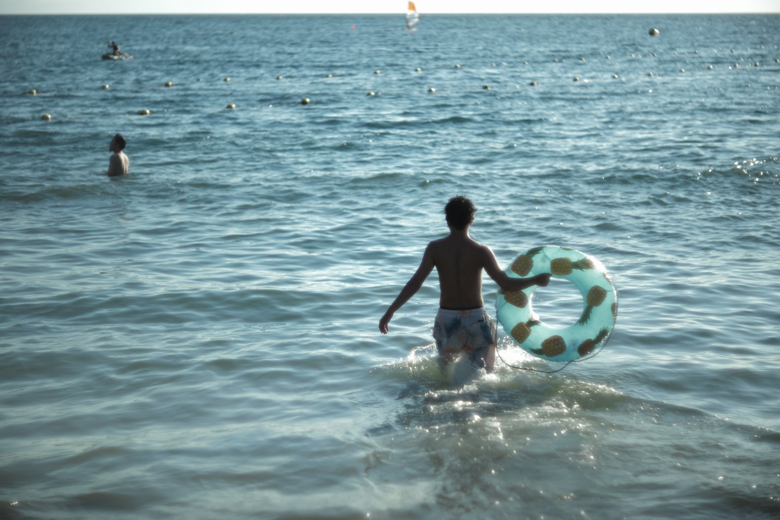 Un ragazzo con un salvagente che cammina nel mare