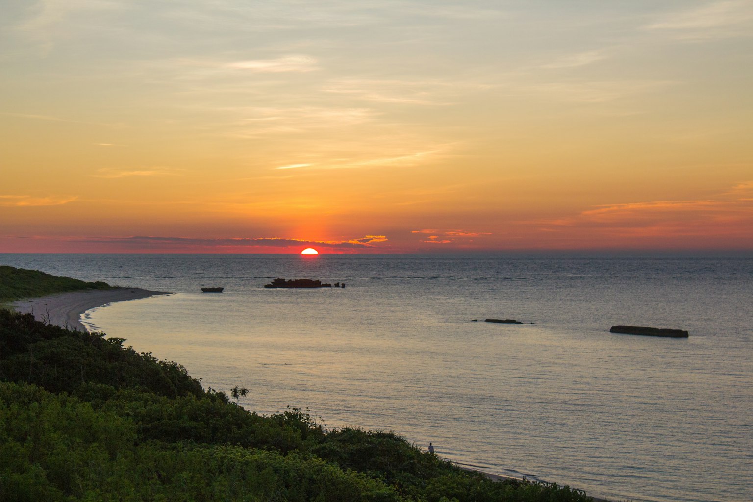Beautiful landscape of sunset over the sea with lush green shoreline and gentle waves