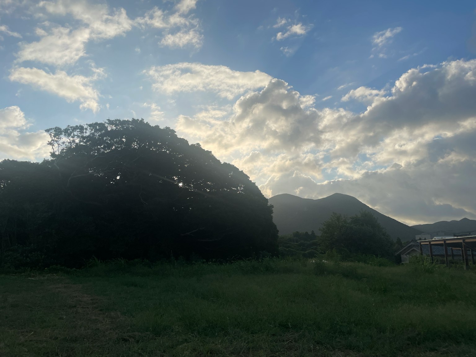 Landschaft mit grünem Grasfeld und Bergen unter blauem Himmel mit Wolken