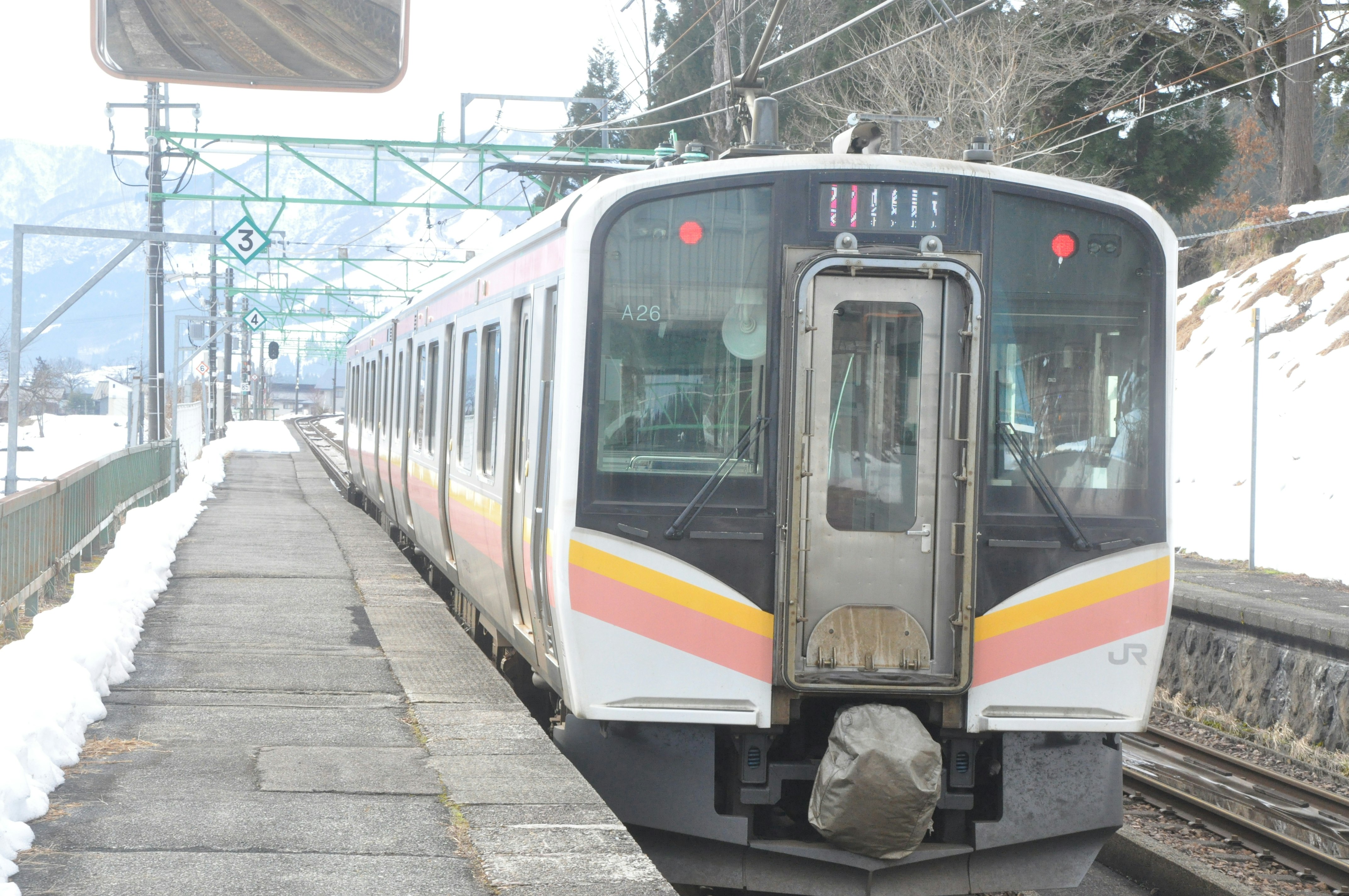 雪のホームに停車する電車の前面