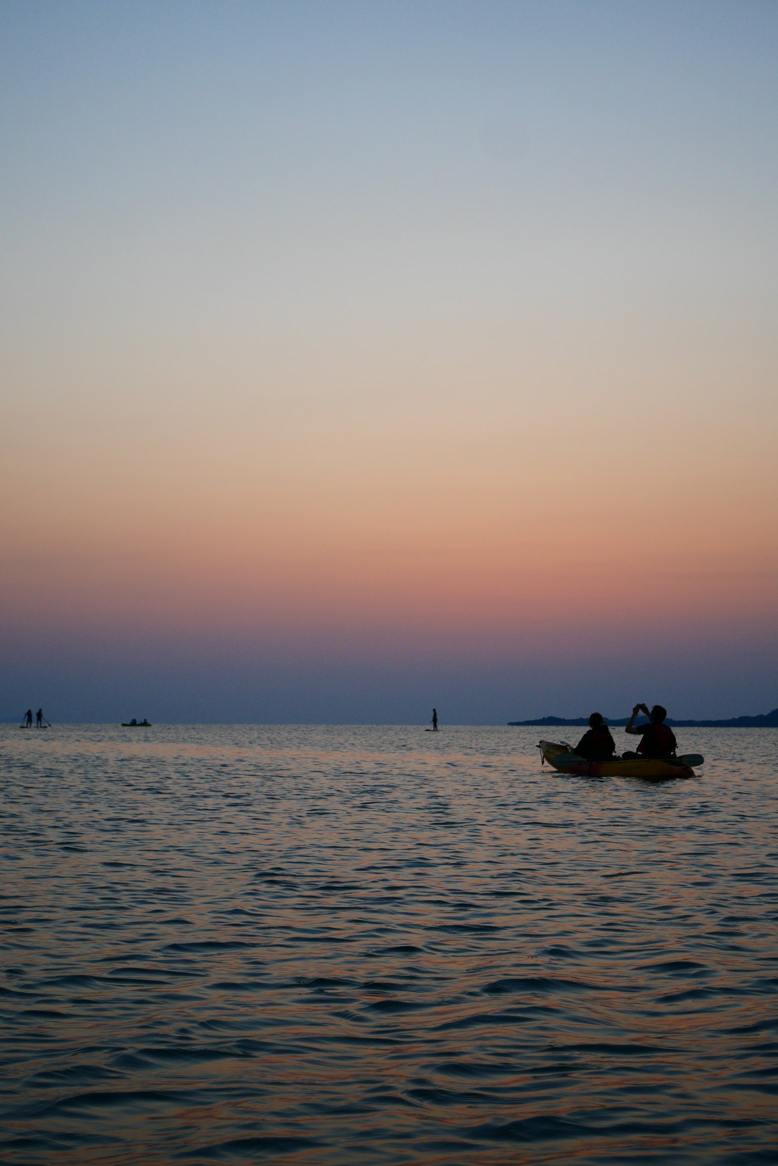 Due persone che si godono il kayak su un mare calmo al tramonto