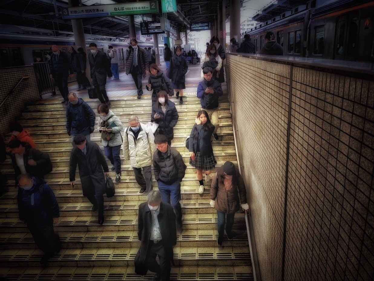 駅のホームの階段で通勤客が行き交う朝の雑踏