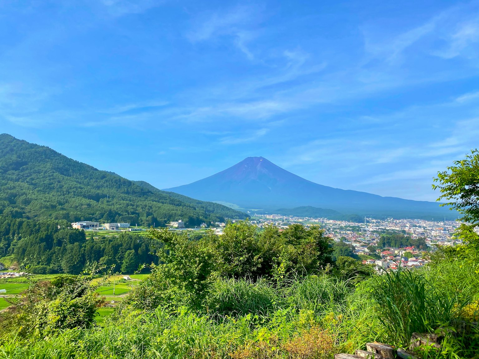 Scenic view of Mount Fuji under a clear blue sky with lush greenery