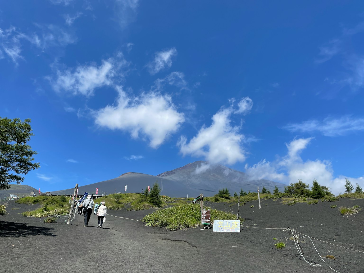 在藍天背景下走在火山地形上的遊客