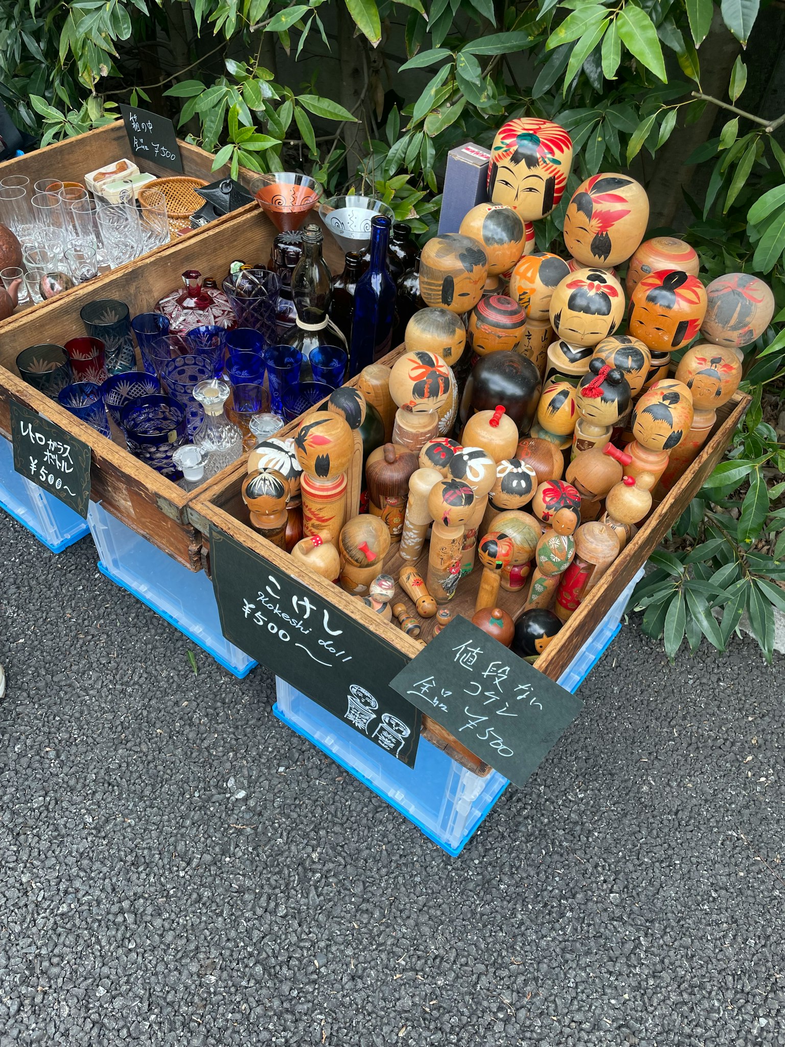 Muñecas de madera y objetos de vidrio exhibidos en un puesto callejero
