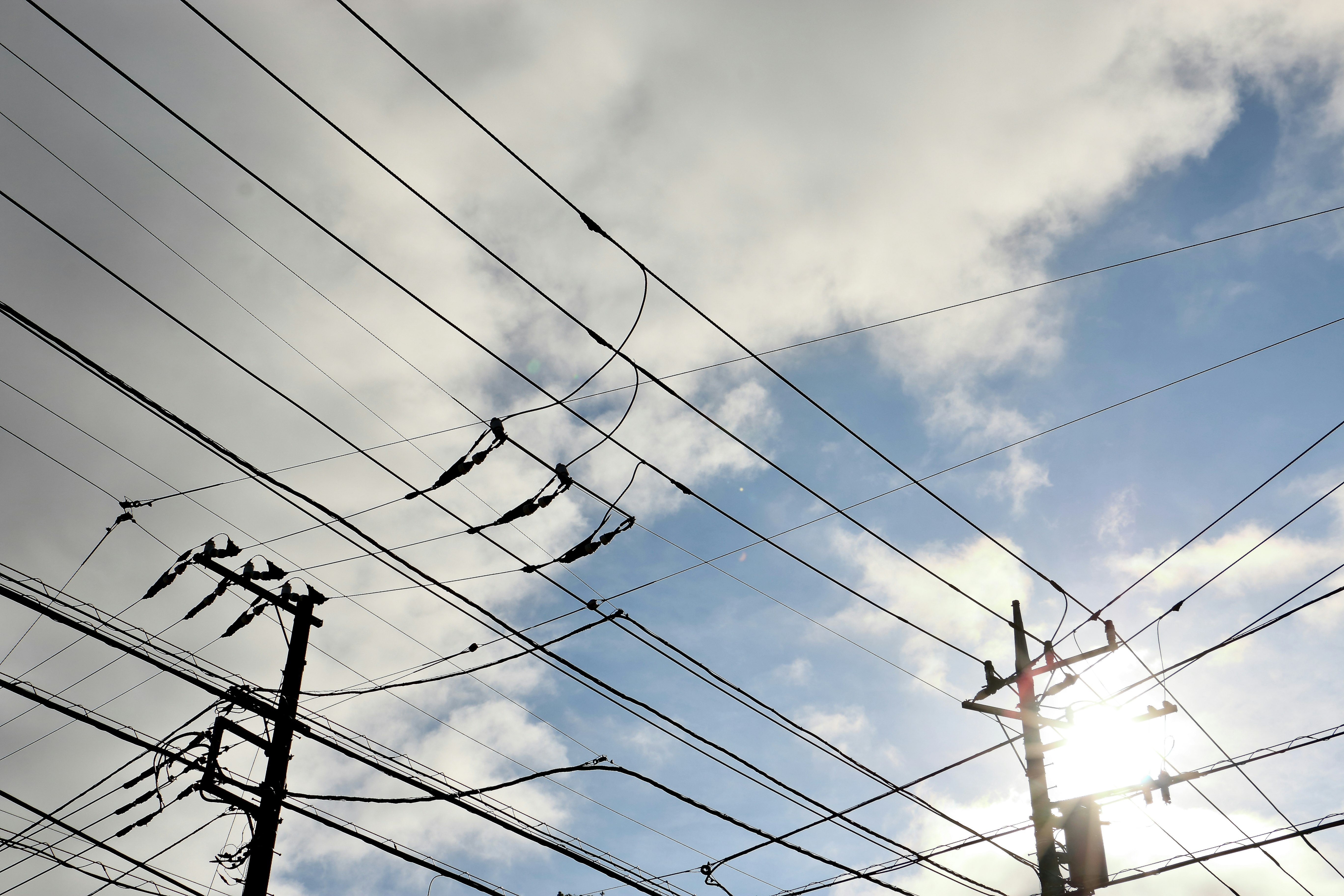 電線が張り巡らされた空の下の街並み