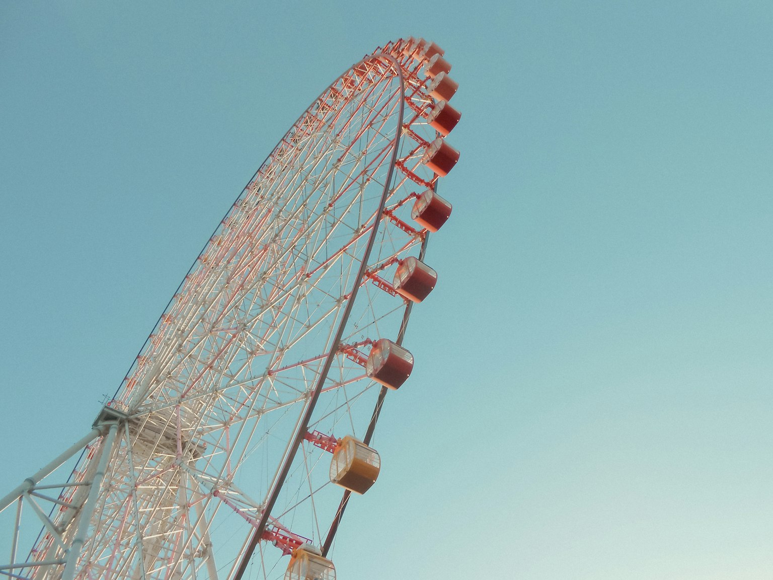 Roda ferris merah dan putih menjulang di latar belakang langit biru