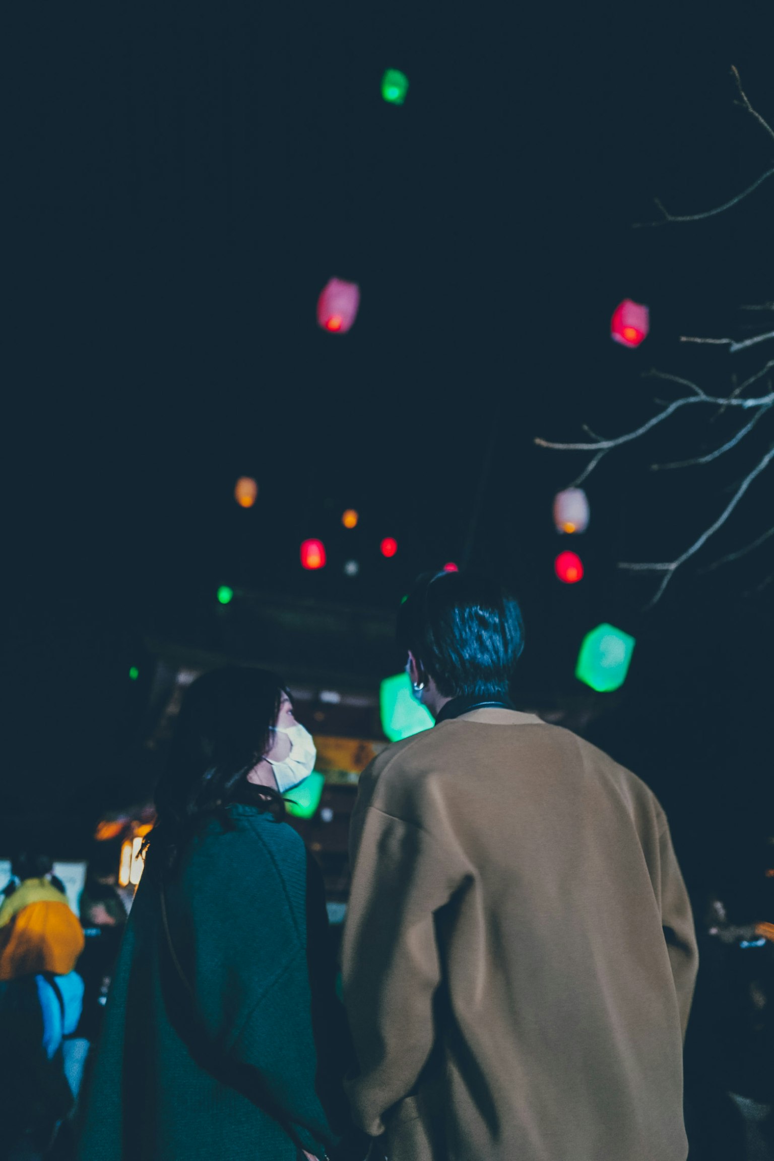 Couple looking up at colorful lanterns in a night sky