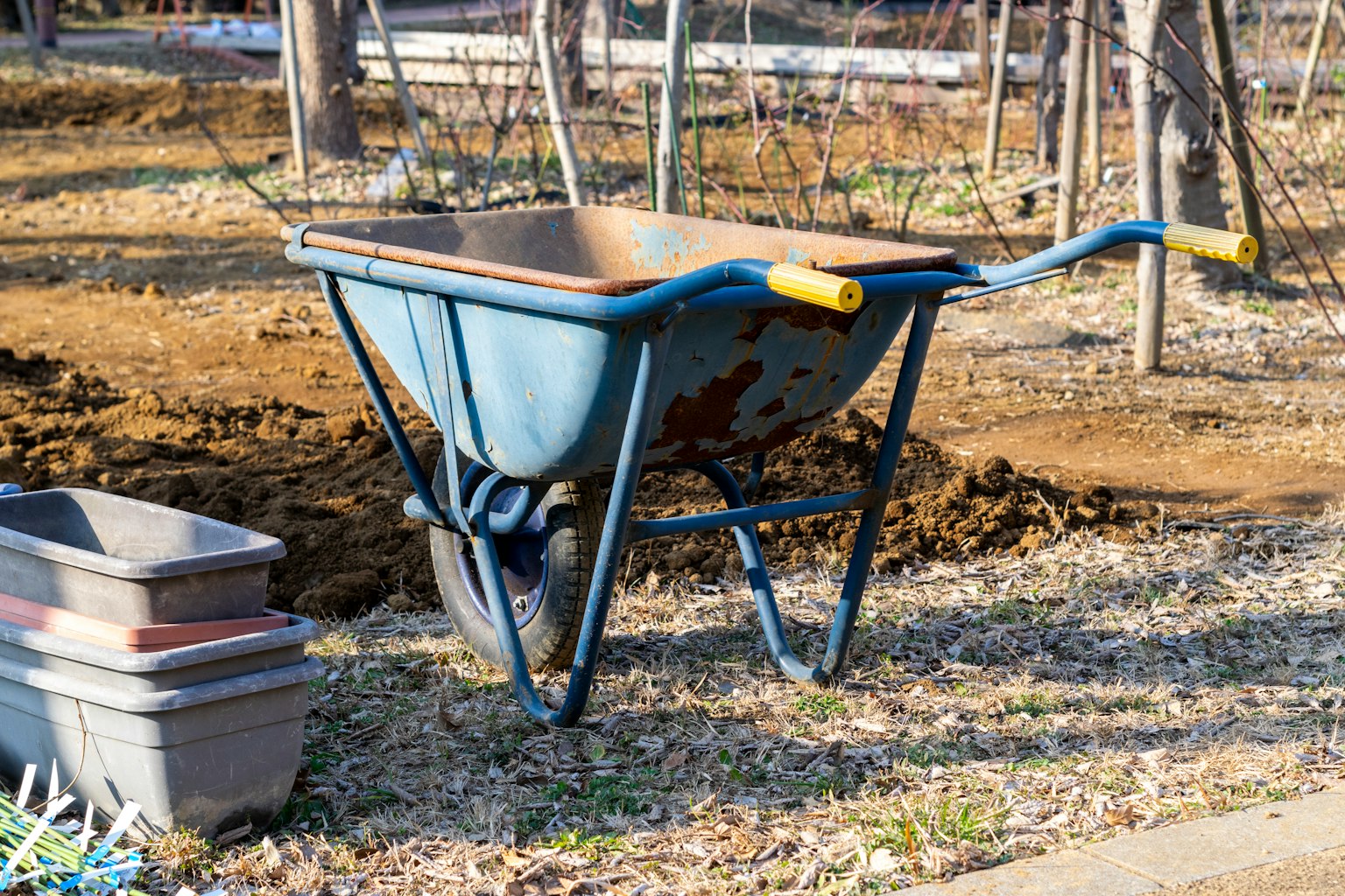 A blue wheelbarrow placed on the ground