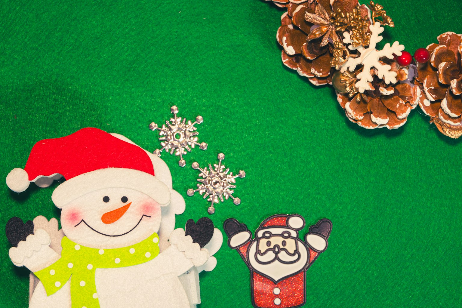 Decoraciones navideñas con recortes de muñeco de nieve y Santa Claus sobre un fondo verde