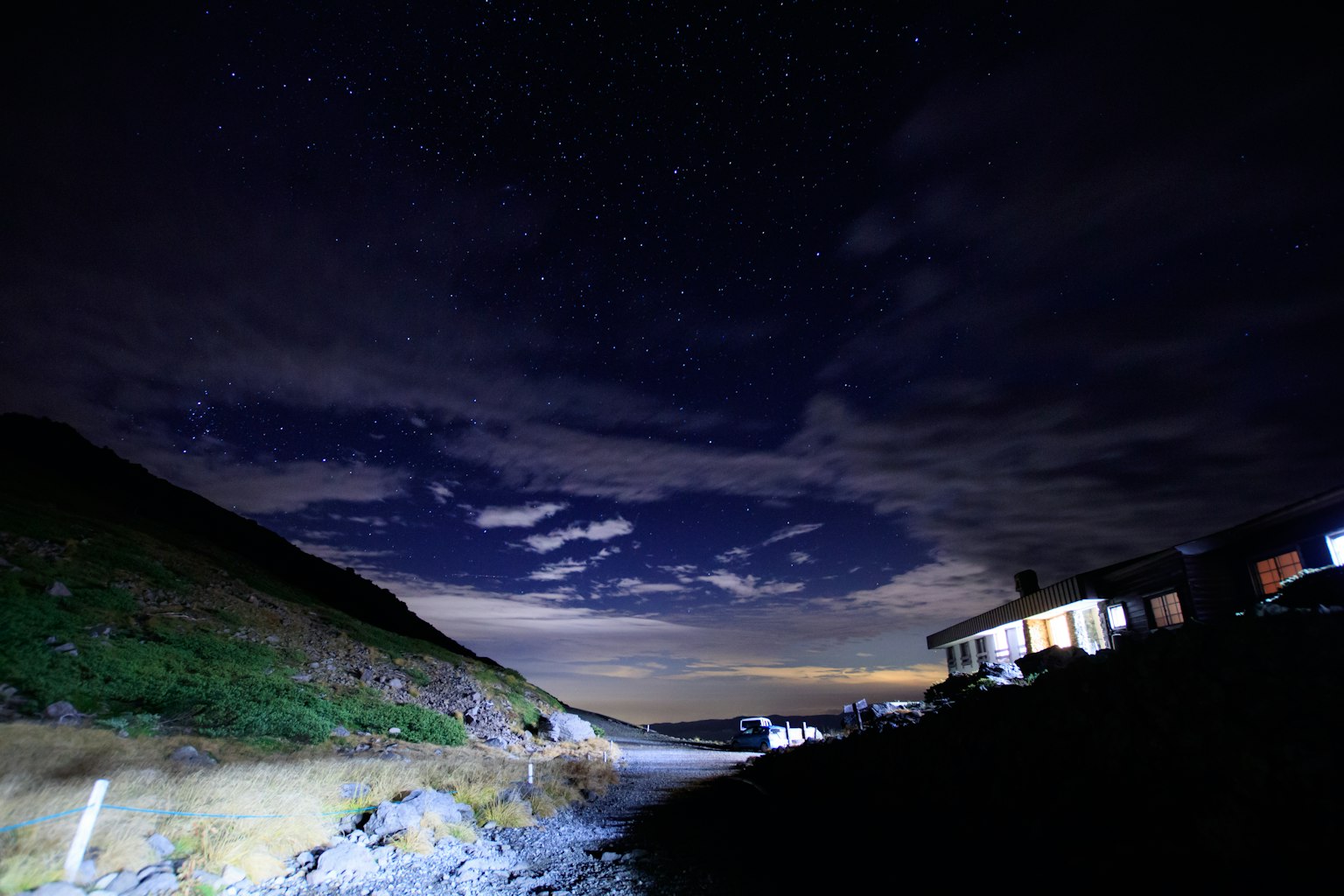 Scène nocturne avec un ciel étoilé et des nuages au-dessus d'une colline