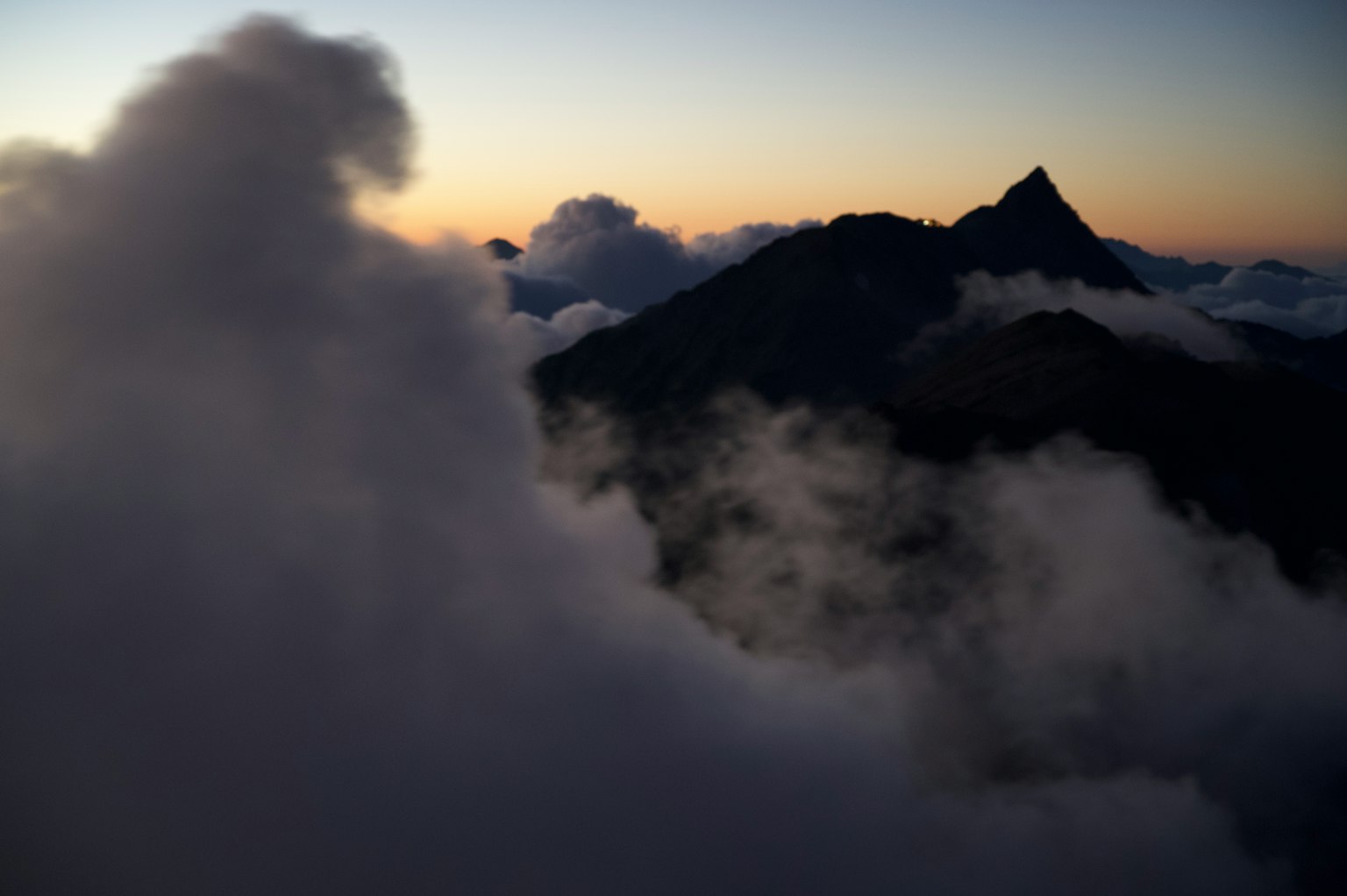 Silhouette di montagna contro un tramonto colorato con nuvole