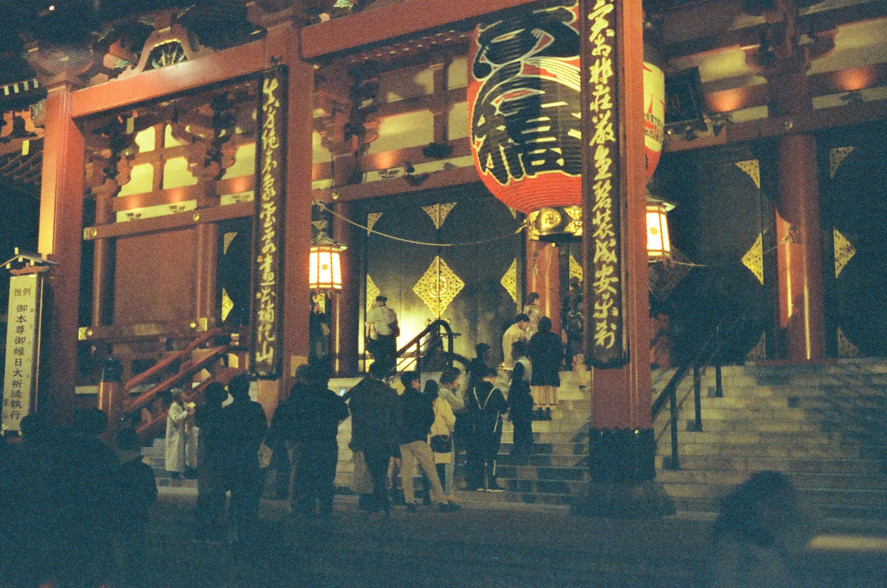 提灯と朱塗りの門が並ぶ夜の神社参道