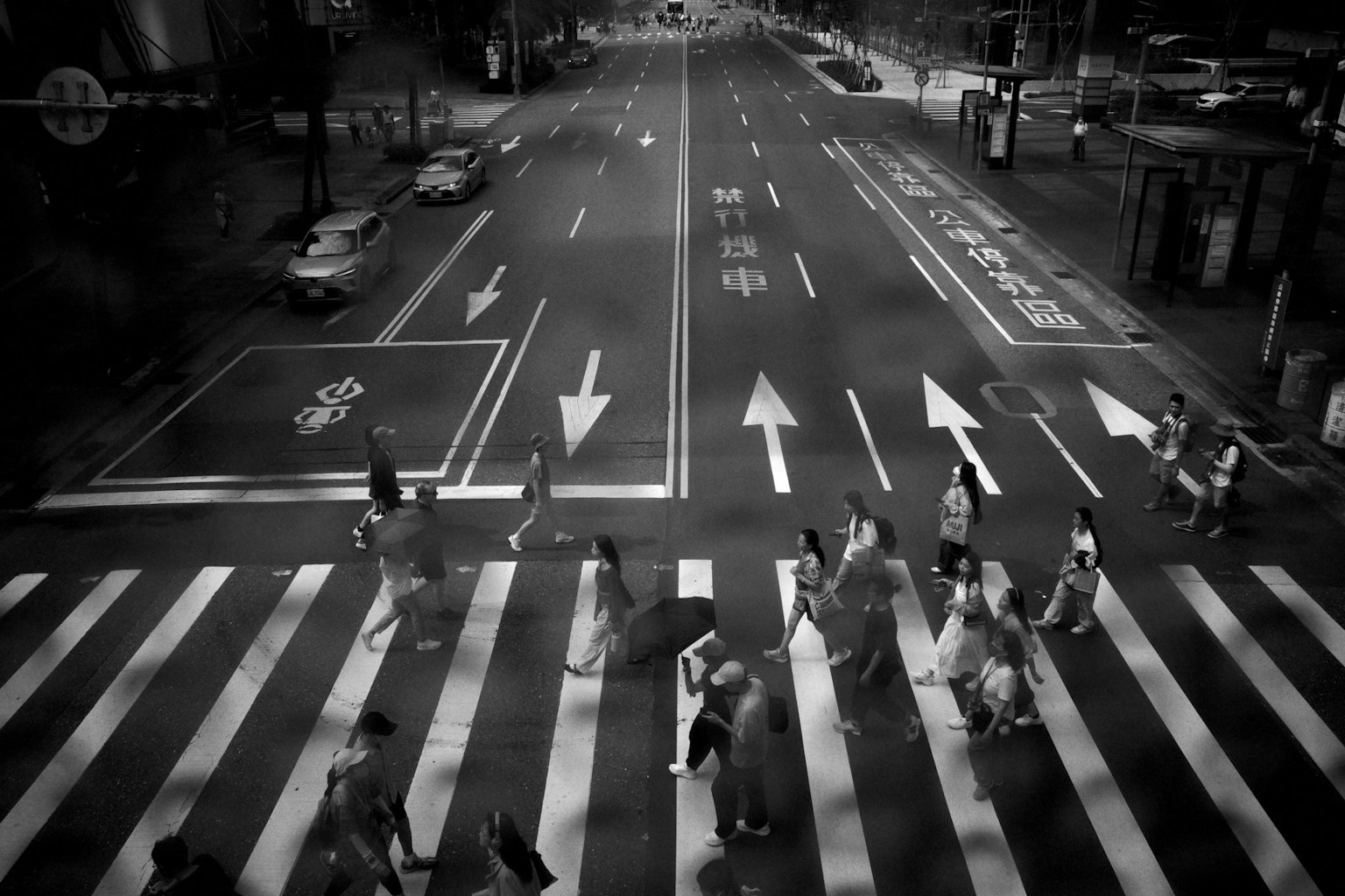 白黒の交差点で横断歩道を渡る人々の群れ