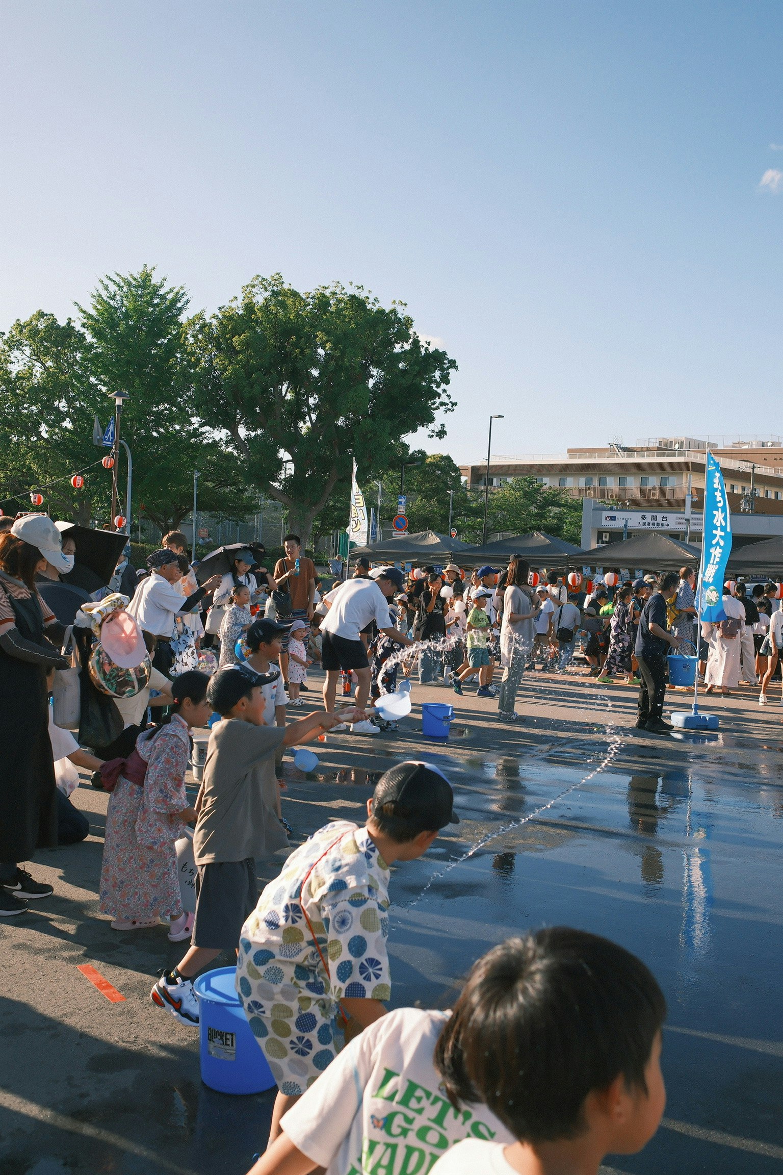 子供たちが水遊びを楽しむ夏祭りの風景 多くの人々が周りに集まっている