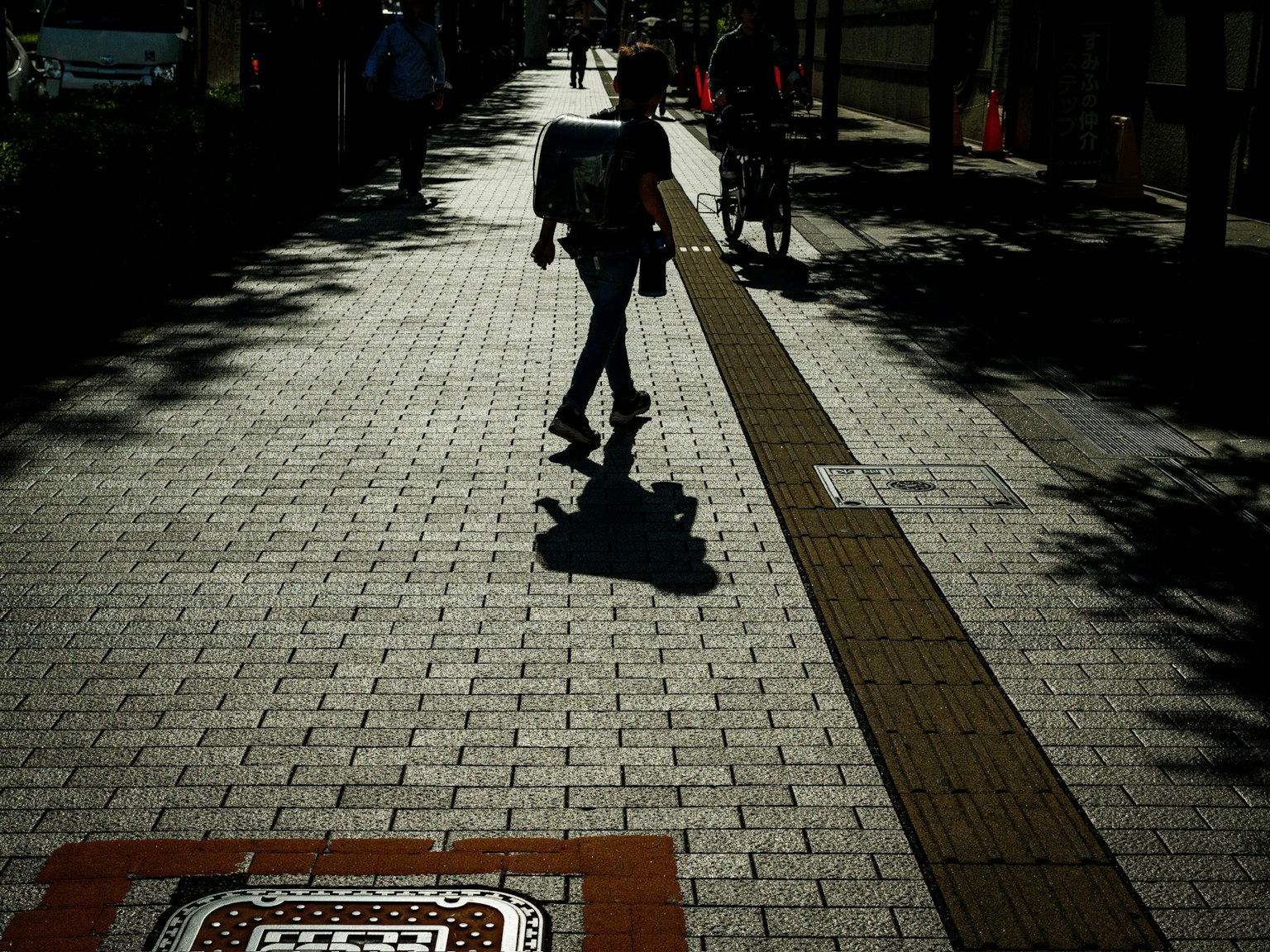 La silhouette di una persona che cammina su un marciapiede luminoso durante il giorno