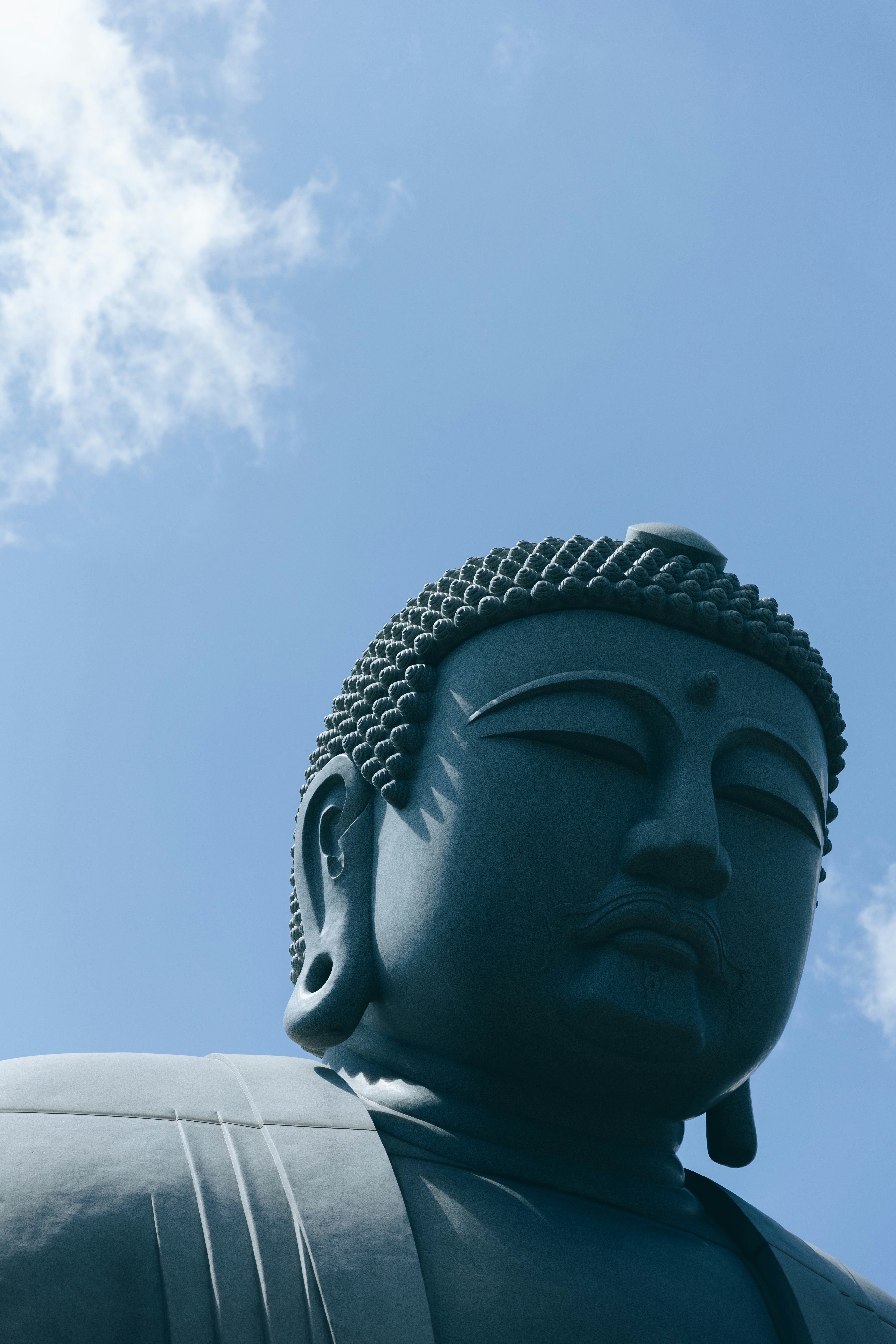 profil d’une grande statue de Bouddha sous un ciel bleu