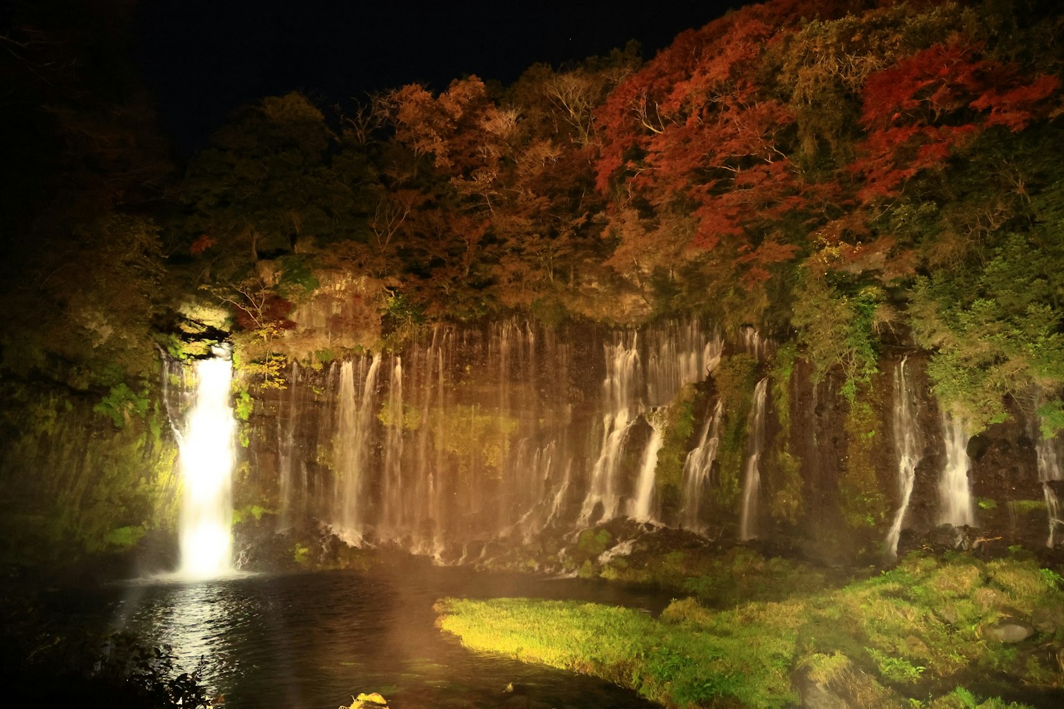 Magnifique scène nocturne d'une cascade avec des feuilles d'automne