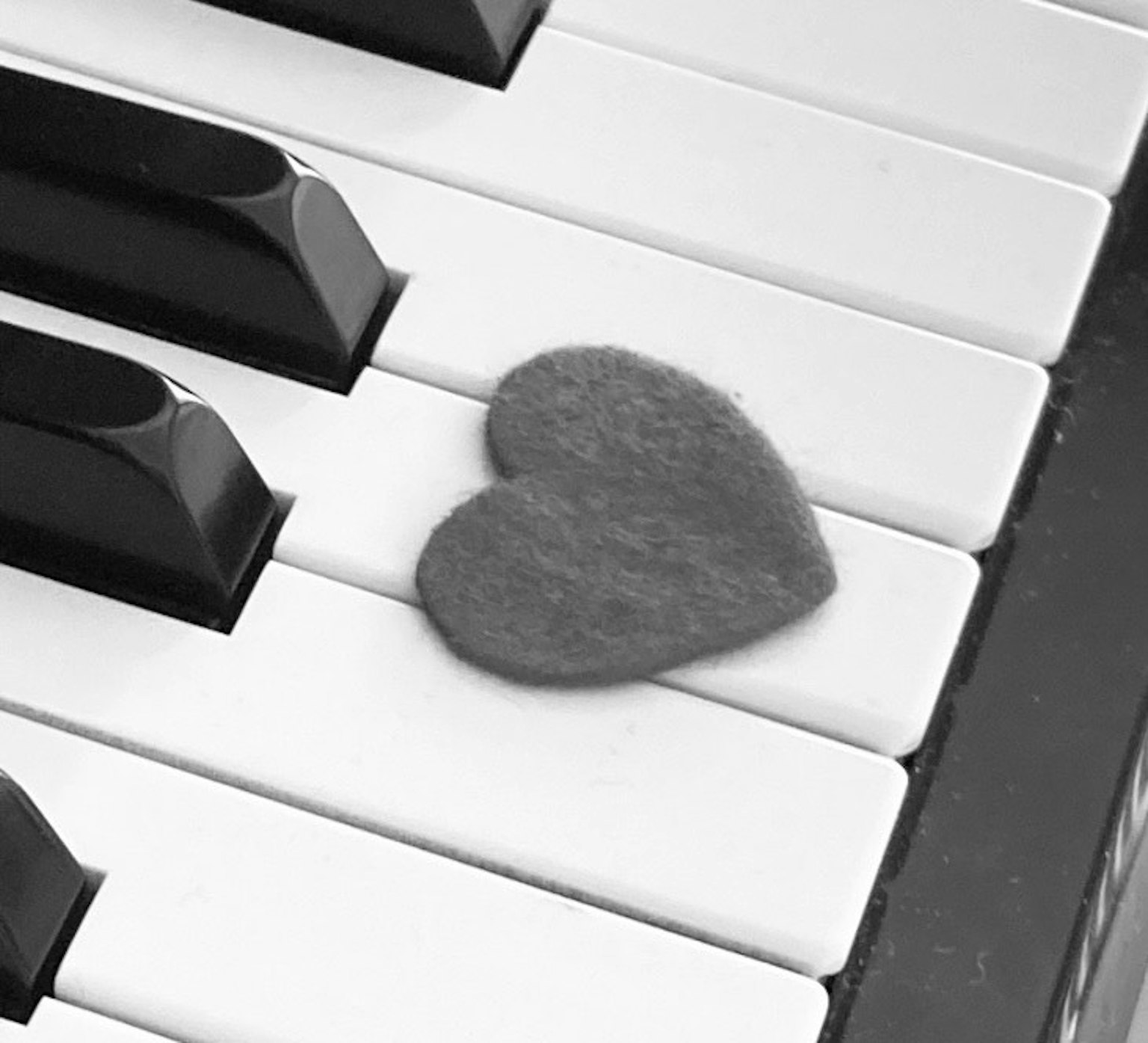 Un pezzo di feltro a forma di cuore su tasti di pianoforte