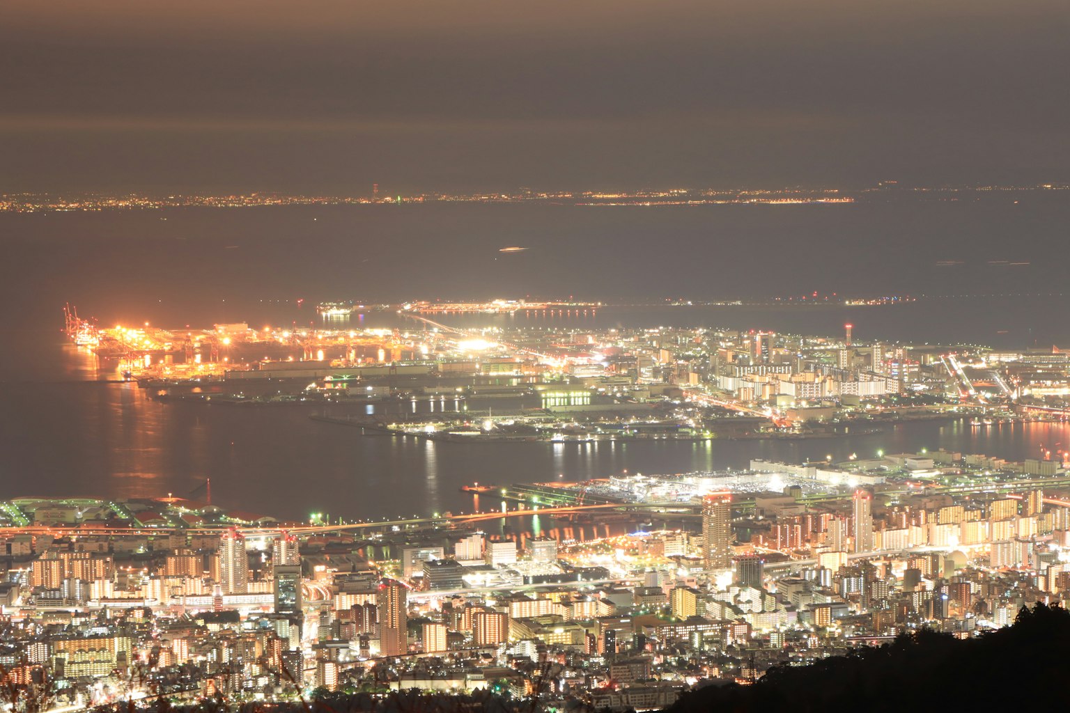 ทิวทัศน์ยามค่ำคืนของเมืองท่าไฟถนนสว่างและการสะท้อนบนผิวน้ำ