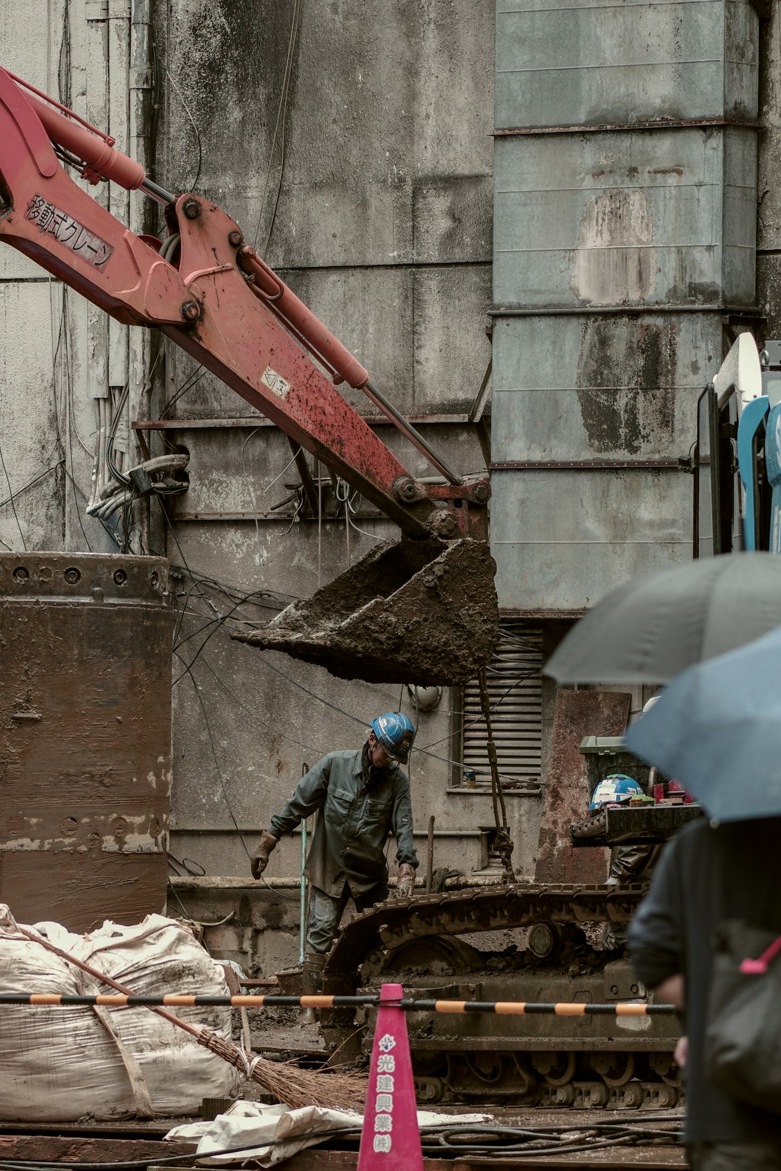 Construction site with machinery and workers in the rain