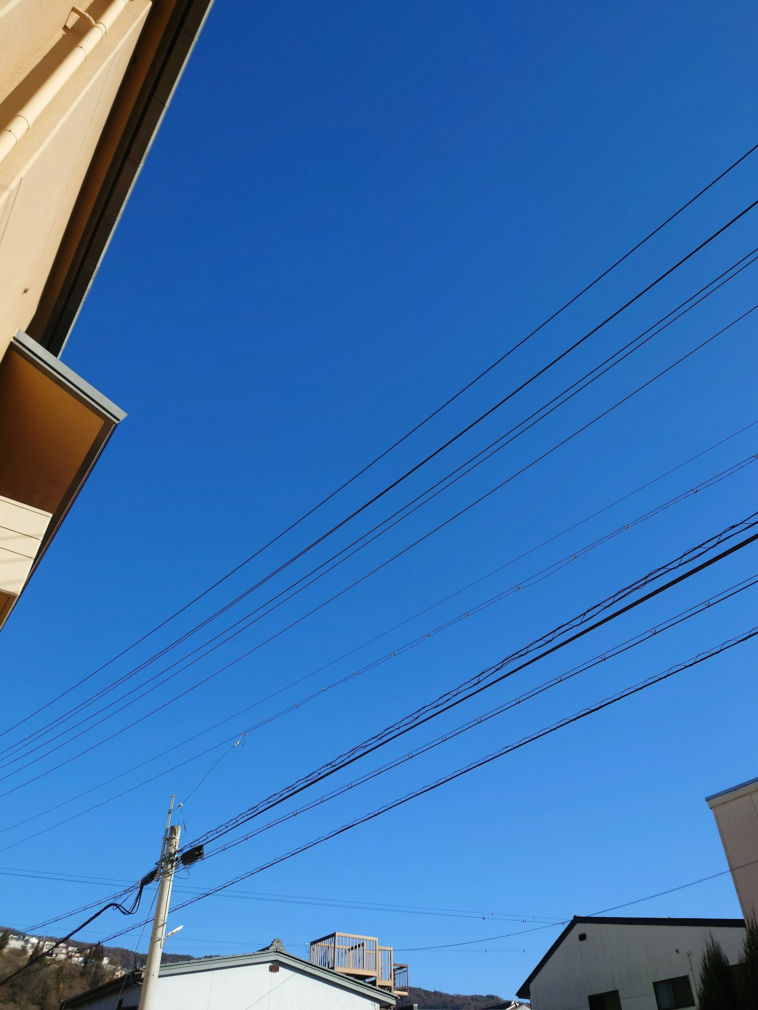 Cielo blu chiaro con linee elettriche in una zona residenziale