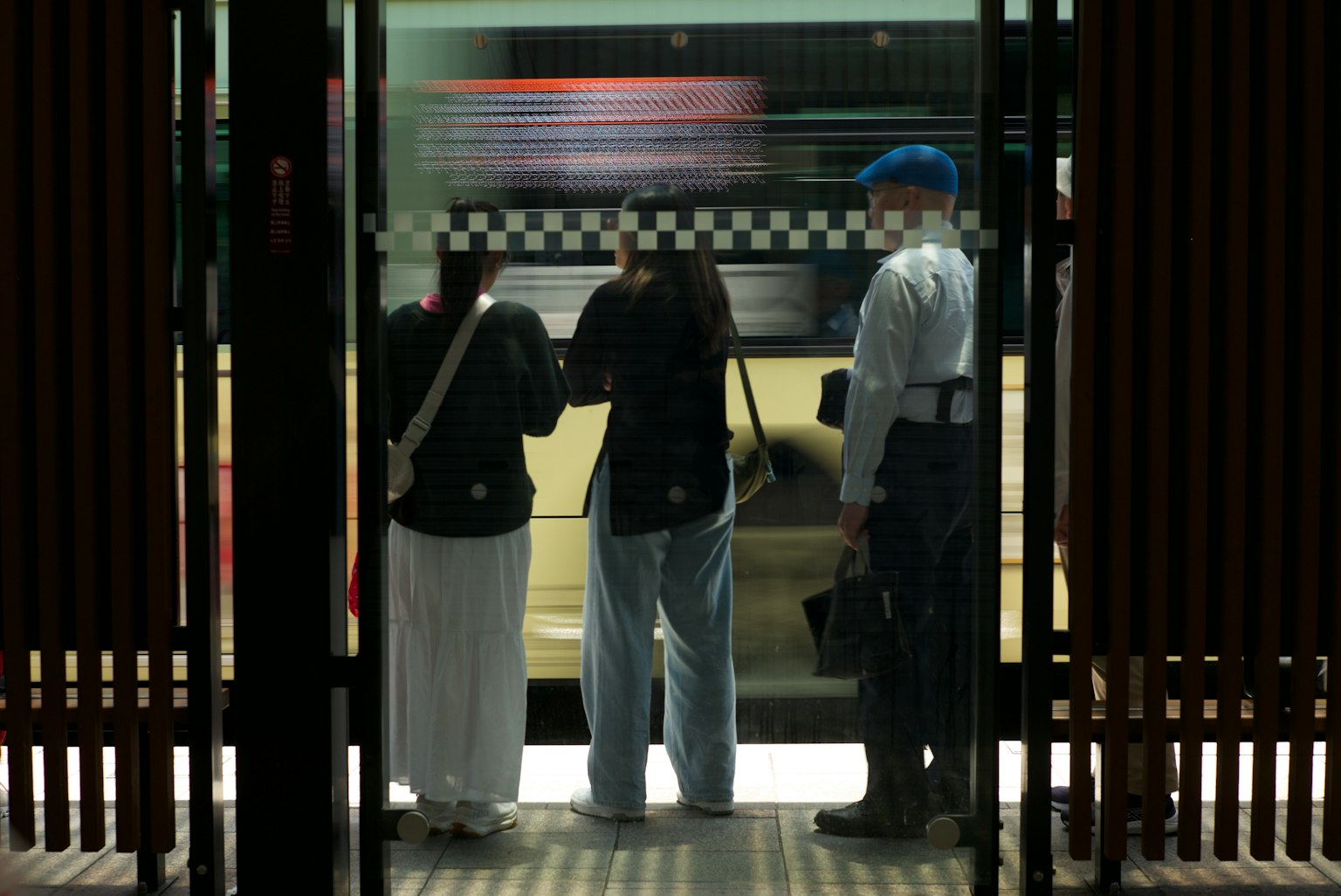 People waiting on a train platform with a blurred train passing