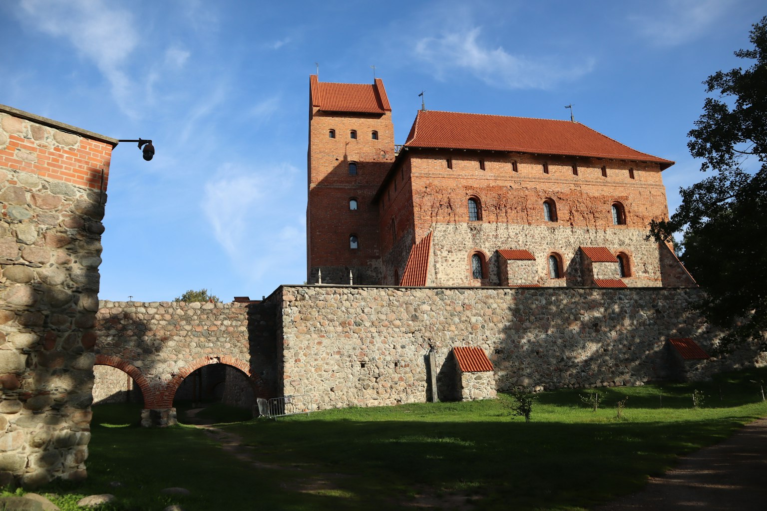 Mittelalterliche Burg mit rotem Dach und Steinmauern unter einem blauen Himmel