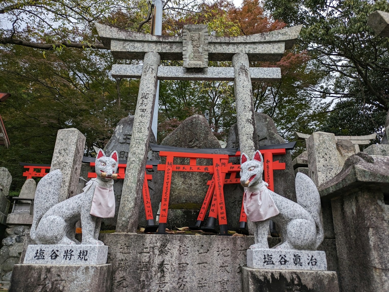 Una scena di santuario con statue di volpe e un torii
