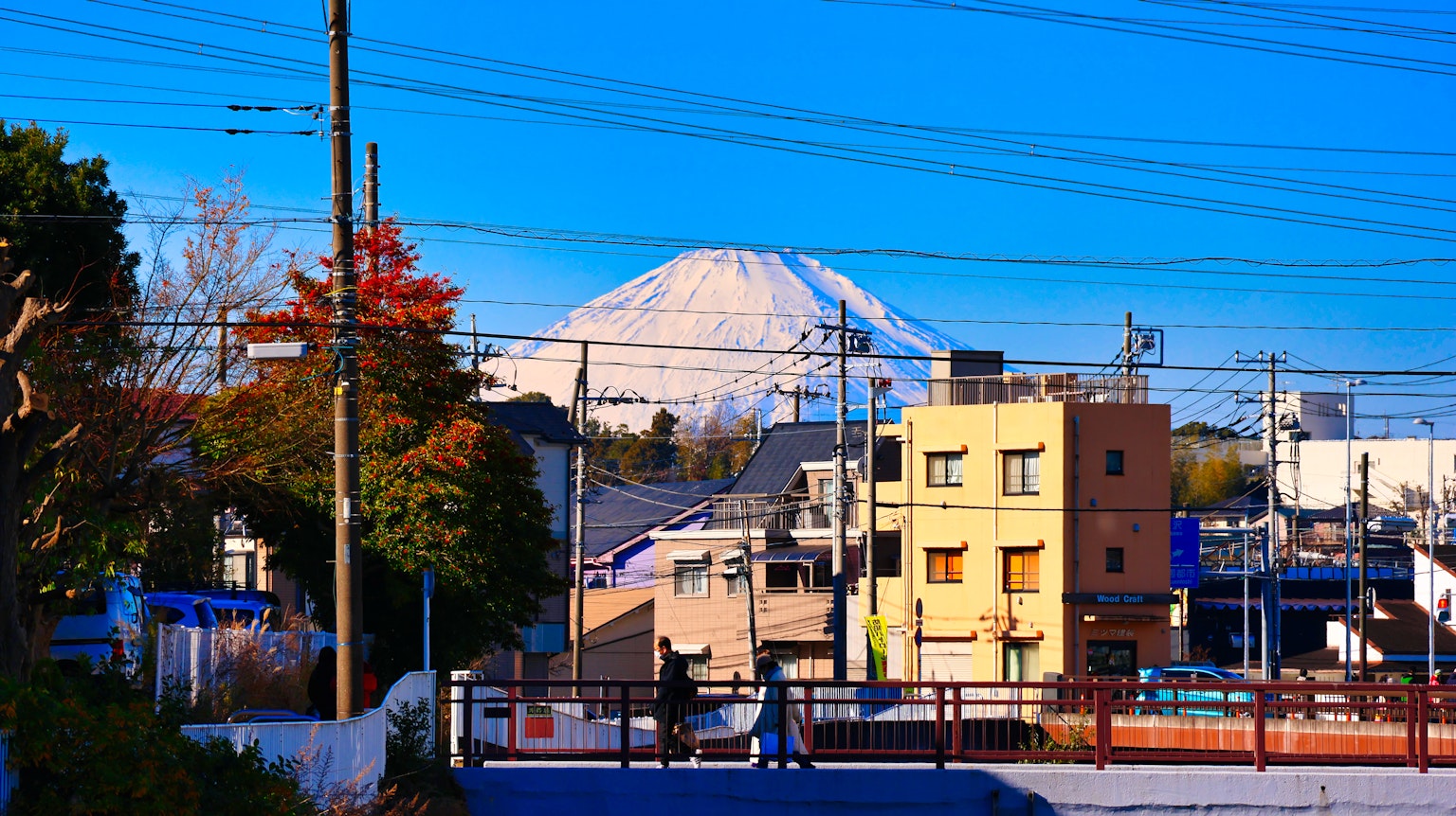 富士山在晴朗的蓝天下耸立，周围是城市景观