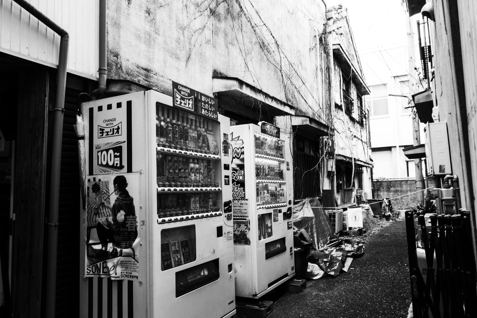 Calle en blanco y negro con máquinas expendedoras y edificios antiguos