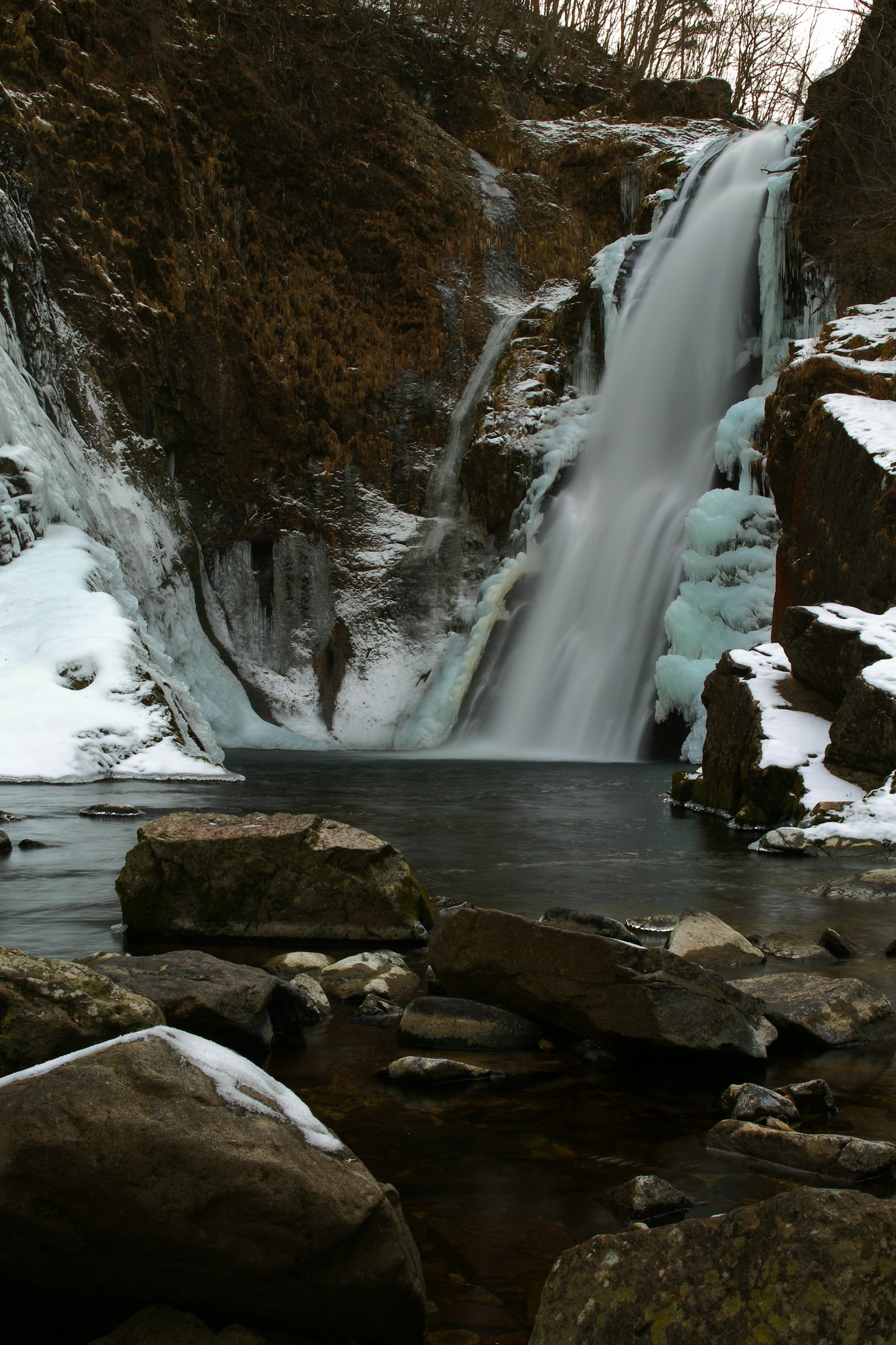 Chute d'eau gelée tombant sur des rochers dans un paysage hivernal