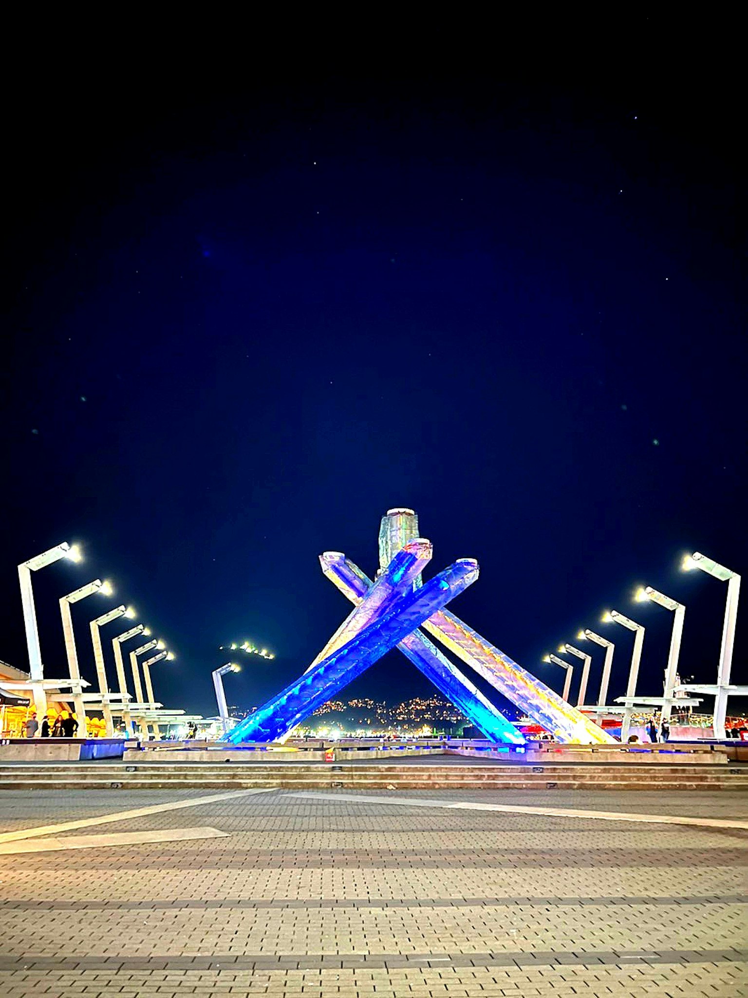 Escena nocturna con un monumento iluminado en azul y estructuras cruzadas
