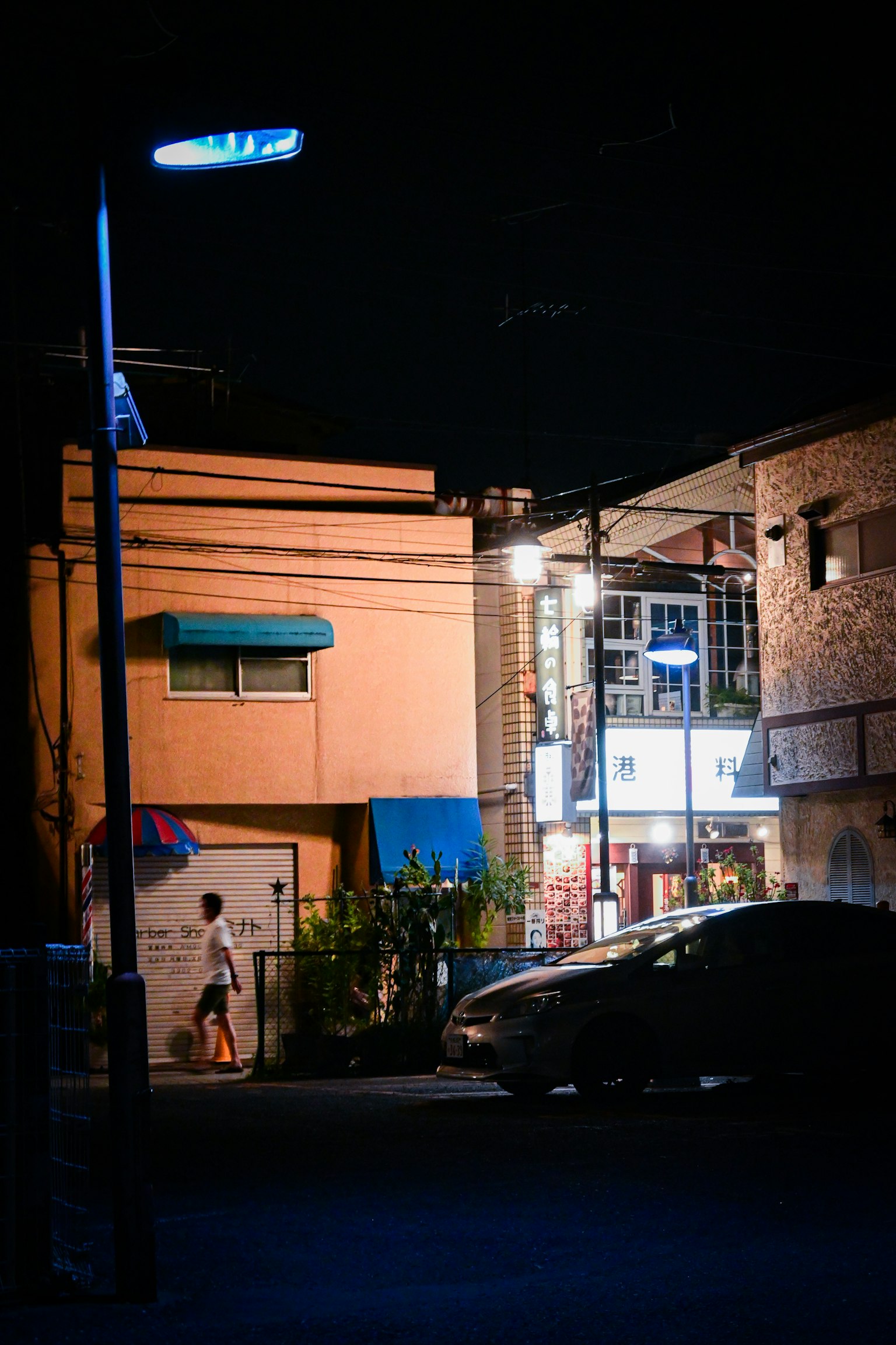 Brightly lit building and car at night on a street corner