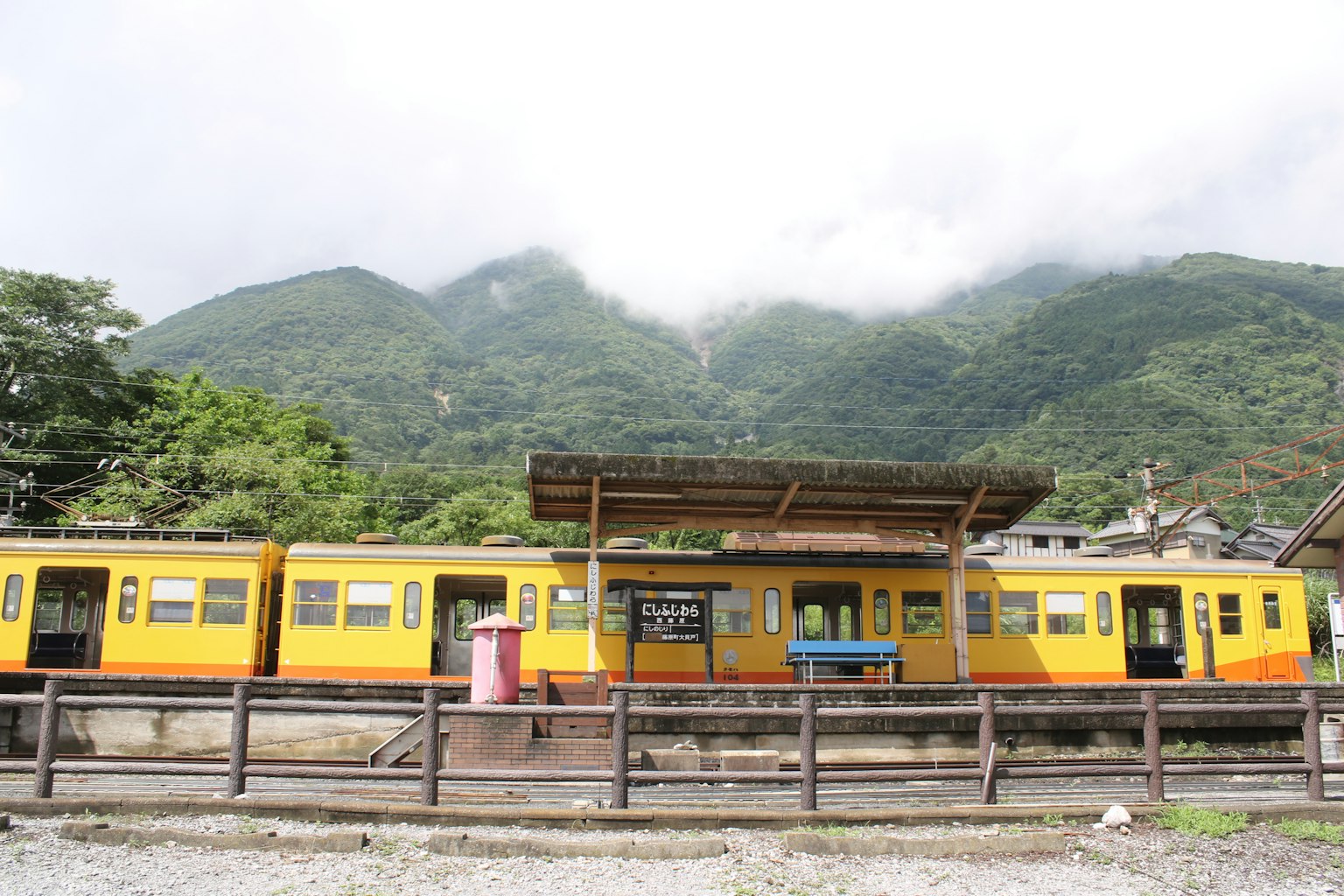 Yellow train at a mountain station with cloudy backdrop