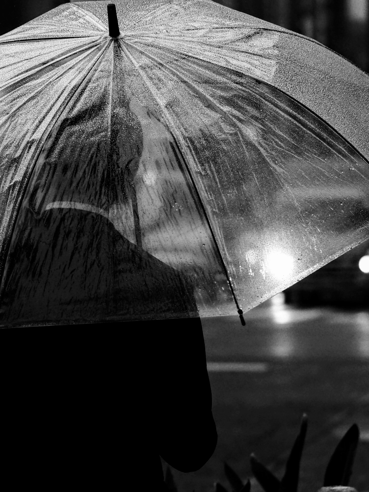Silhouette di un uomo con un ombrello sotto la pioggia in una strada di città