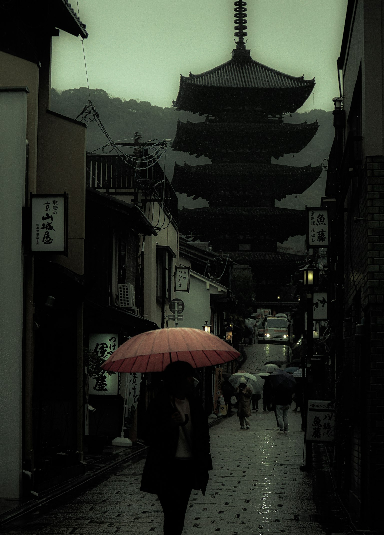 Street scene with a person holding a red umbrella and an ancient pagoda