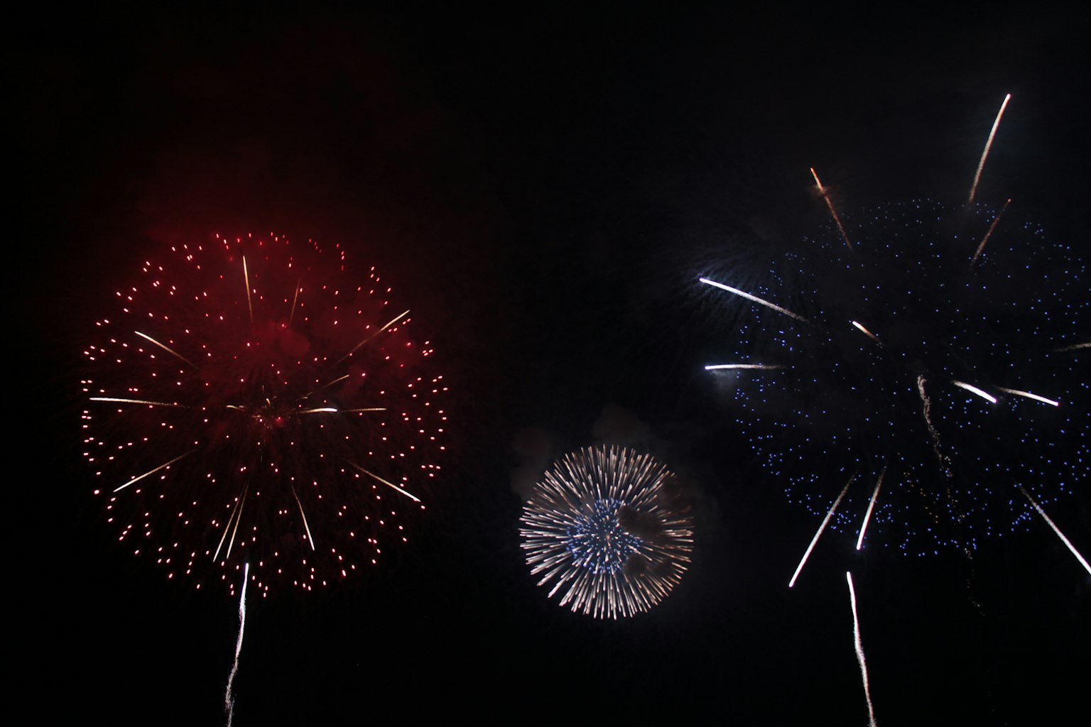 Des feux d'artifice éclatent dans le ciel nocturne avec des couleurs rouges et bleues