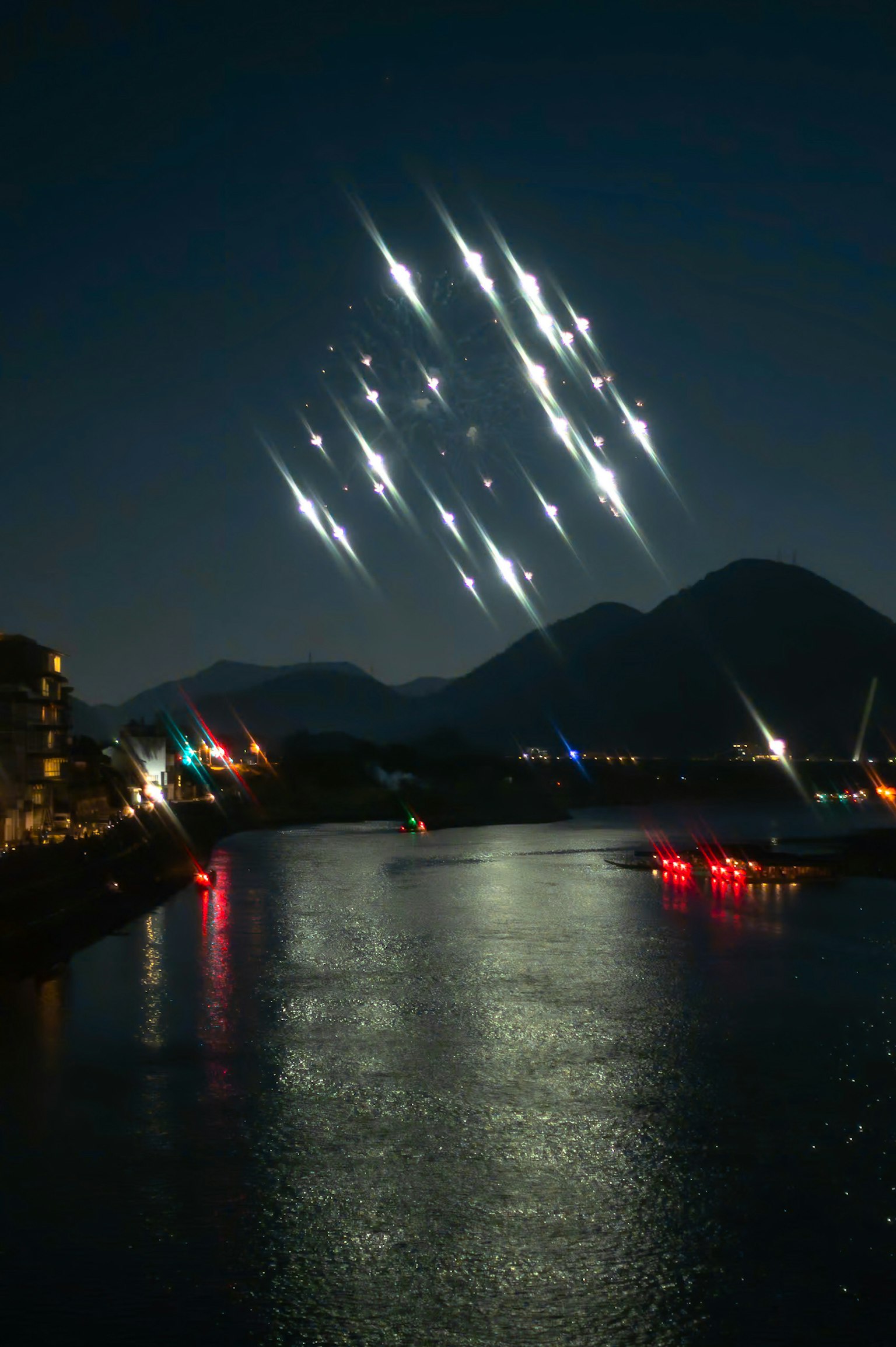 Strisce di luce nel cielo notturno che si riflettono su un fiume calmo