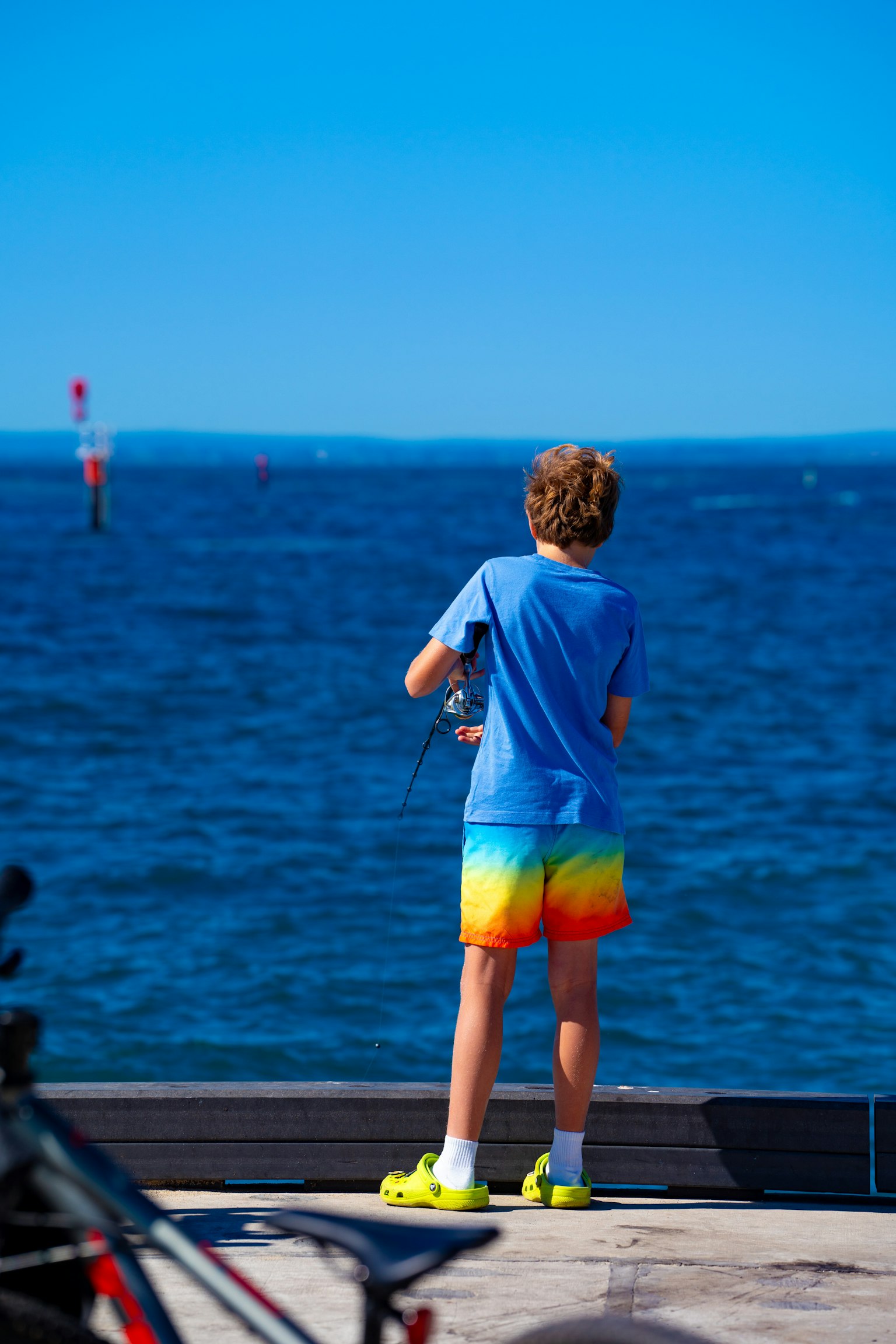 Boy looking at the sea wearing colorful shorts