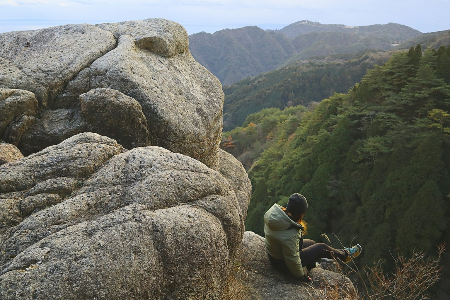 Person sitting on a rock with a scenic mountain view