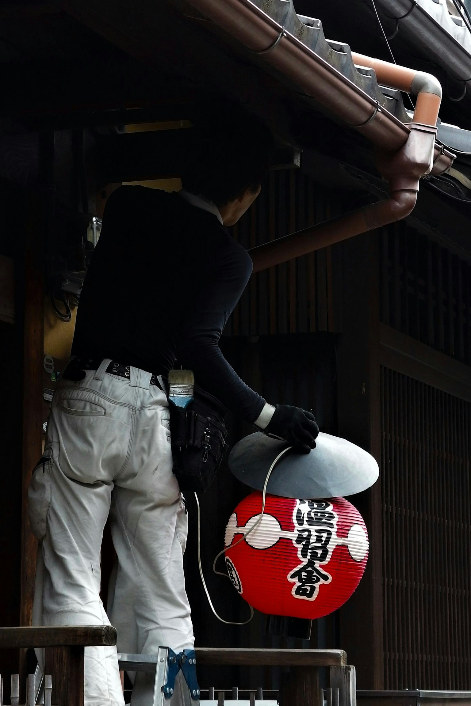 伝統的な日本の建物の屋根に提灯を取り付ける作業員